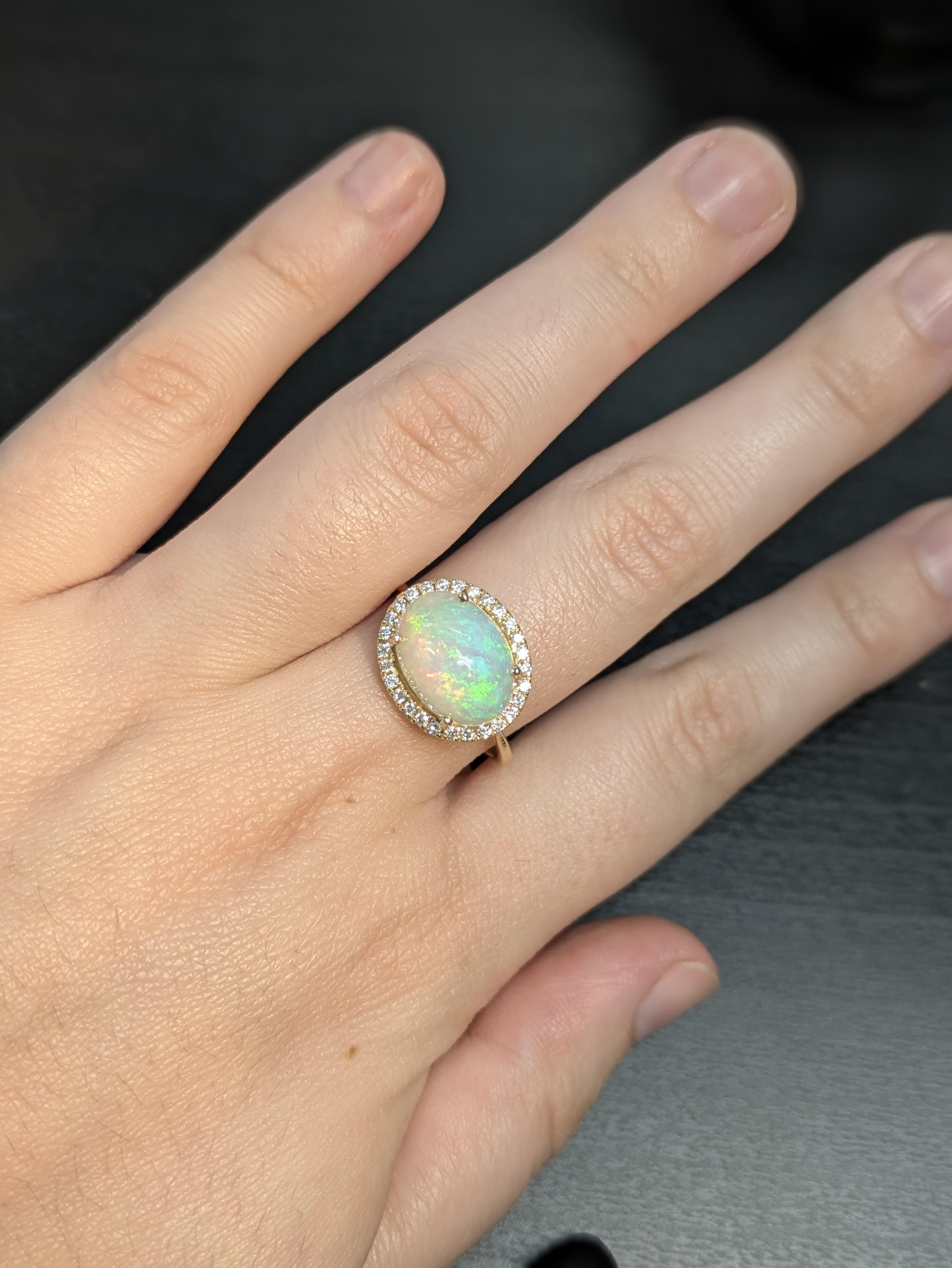 A captivating 3.15ct oval Ethiopian opal takes center stage in this stunning ring, radiating vibrant flashes of color. Set in 14k gold (2.55g), the 12x10mm opal is elegantly framed by 28 sparkling diamonds totaling 0.22cttw, adding a touch of
