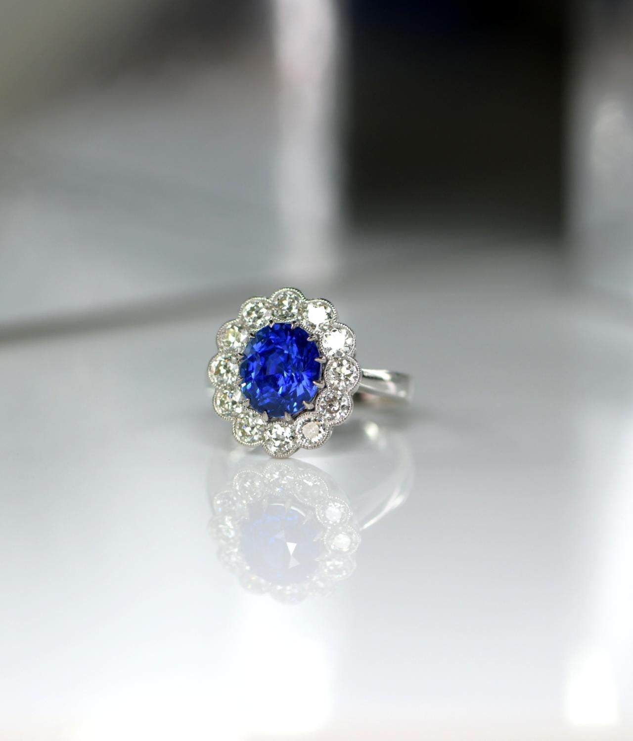 This sapphire is top quality royal blue colour. It has an extraordinary fire that will always catch the eye. This amazing stone is set in the centre of a timeless classic cluster design. The surrounding diamonds are also bright and have good fire.