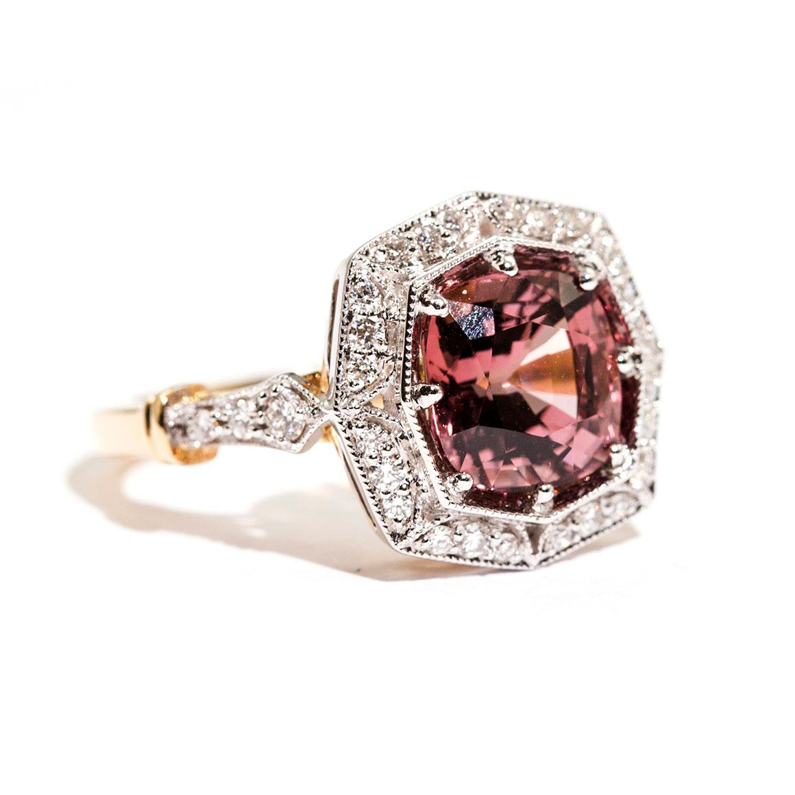 Forged in 18 carat yellow and white gold is this vintage inspired halo ring that features a striking 3.16 carat bright reddish pink cushion cut natural spinel complimented by a total of 0.31 carats of sparkling round brilliant cut diamonds. We have