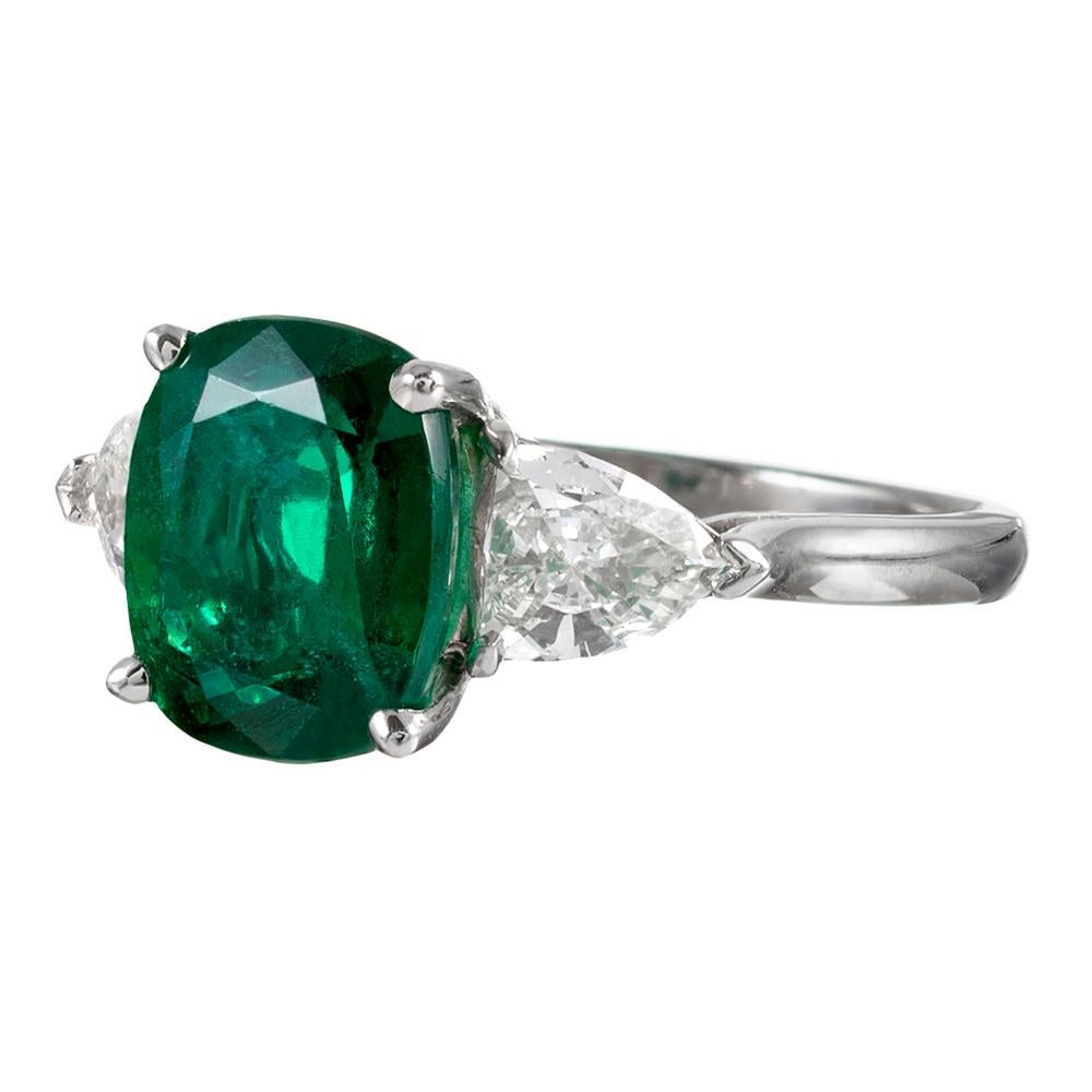 The emerald exhibits intense, grassy green color, weighing 3.16 carats. It is flanked by a pair of shield-shaped white diamonds that one must look closely at to appreciate, as they can at first glance appear to be trillions. The shield diamonds