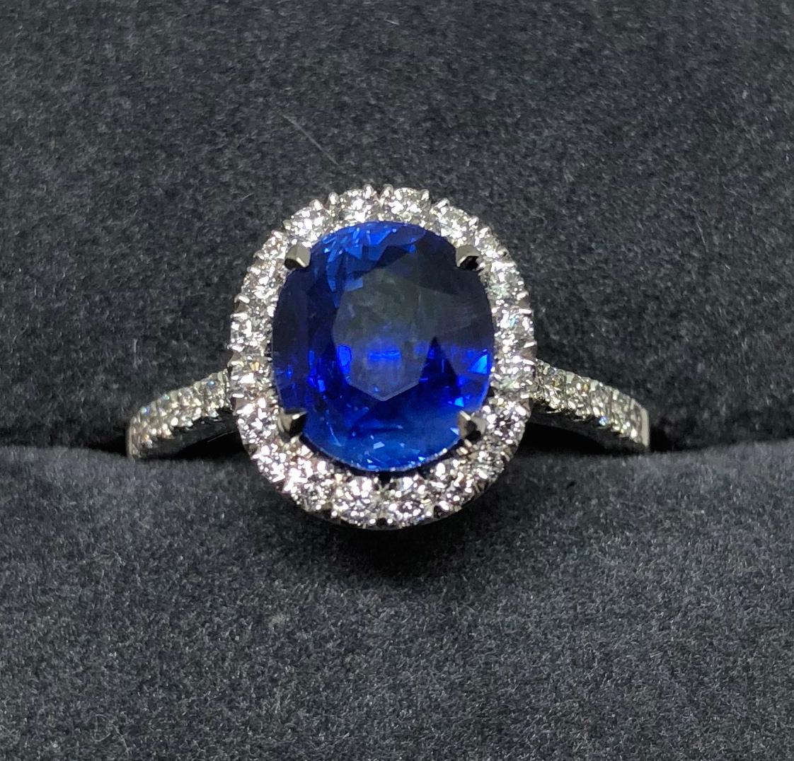 A beautifully set 3.17 carat Oval Sapphire surrounded by a Halo cluster of diamonds with diamond set shoulders. The stones are set in Platinum designed and handmade by E & W Hopkins Ltd. The ring size is US 5 1/2.
