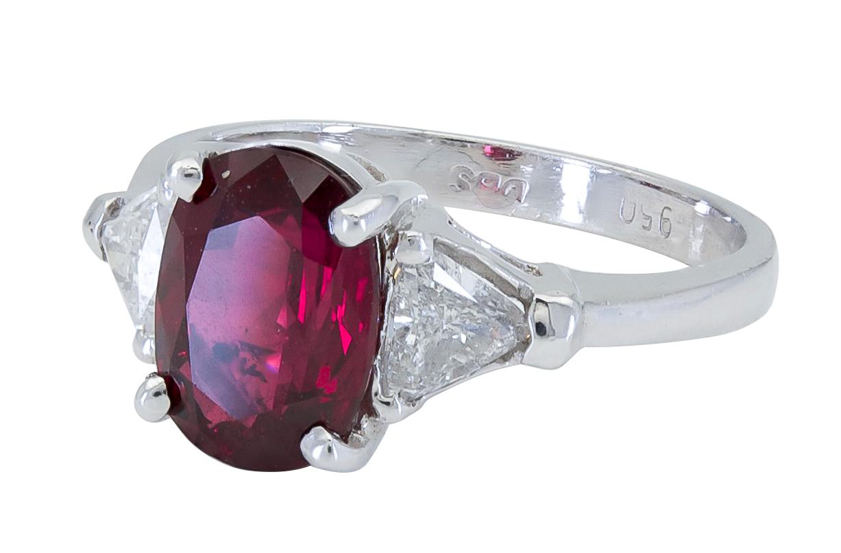 A classic engagement ring style featuring a color-rich oval cut ruby accented by brilliant trillion (triangular) diamonds. Set in a tapering platinum mounting.
Ruby weighs 3.17 carats.
Side Diamonds weigh 0.53 carats total.
Size 7.5 US
