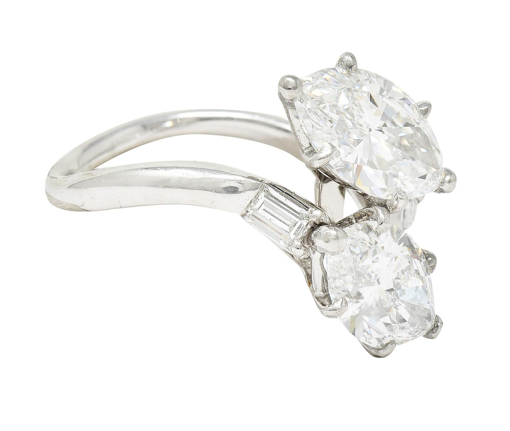 Bypass style ring features two basket set marquise cut diamonds

One weighing 1.49 carats with D color and VS1 clarity

Opposing weighs 1.48 carats with E color and VVS2 clarity

Shoulders are accented by rectangular step cut diamonds - eye clean