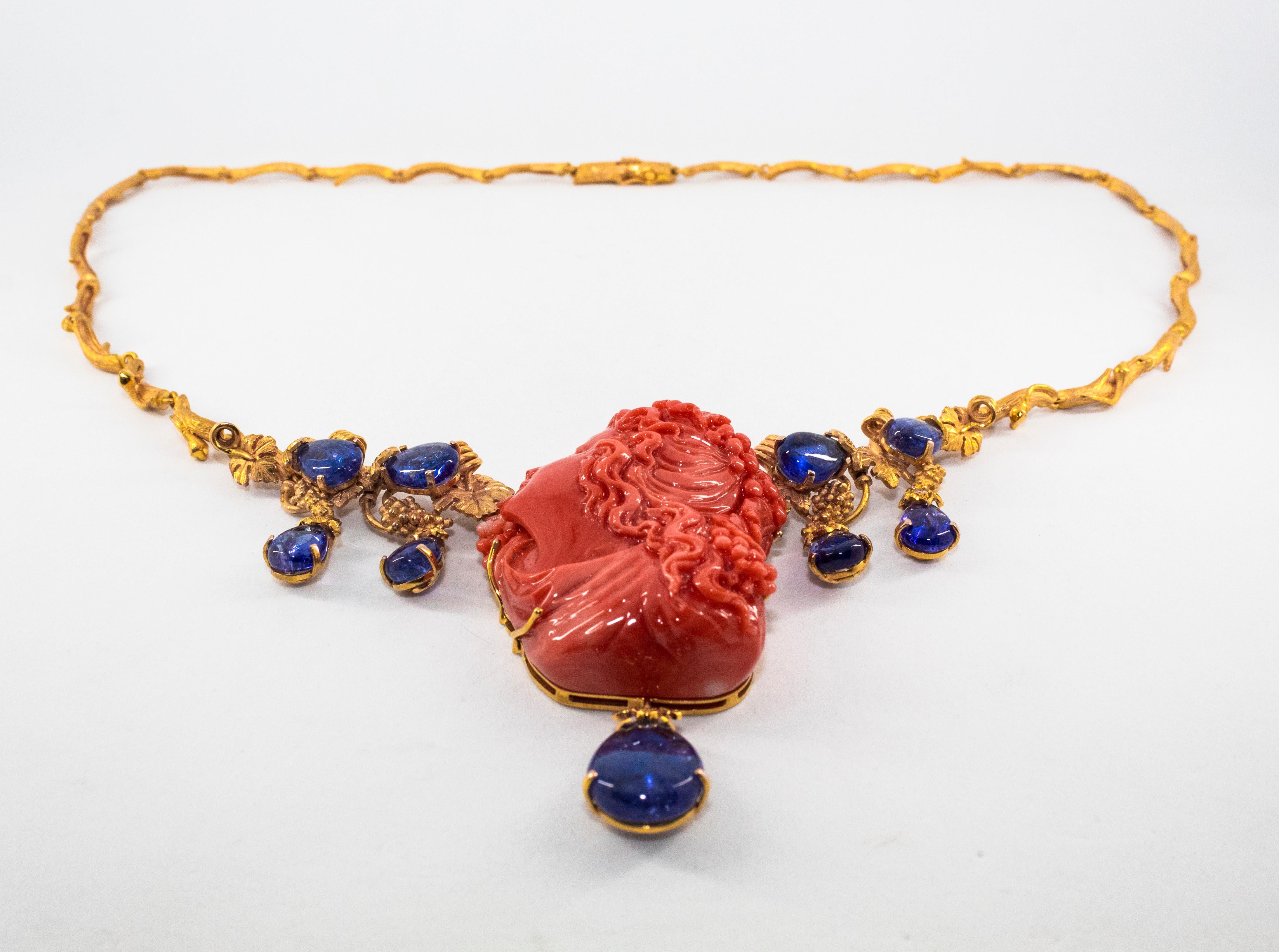 This Necklace is made of 14K Yellow Gold.
This Necklace has 0.33 Carats of White Diamonds.
This Necklace has 31.60 Carats of Tanzanite.
This Necklace has Red Mediterranean (Sardinia, Italy) Carved Coral.
The Girl made of Red Coral is Arianna, wife