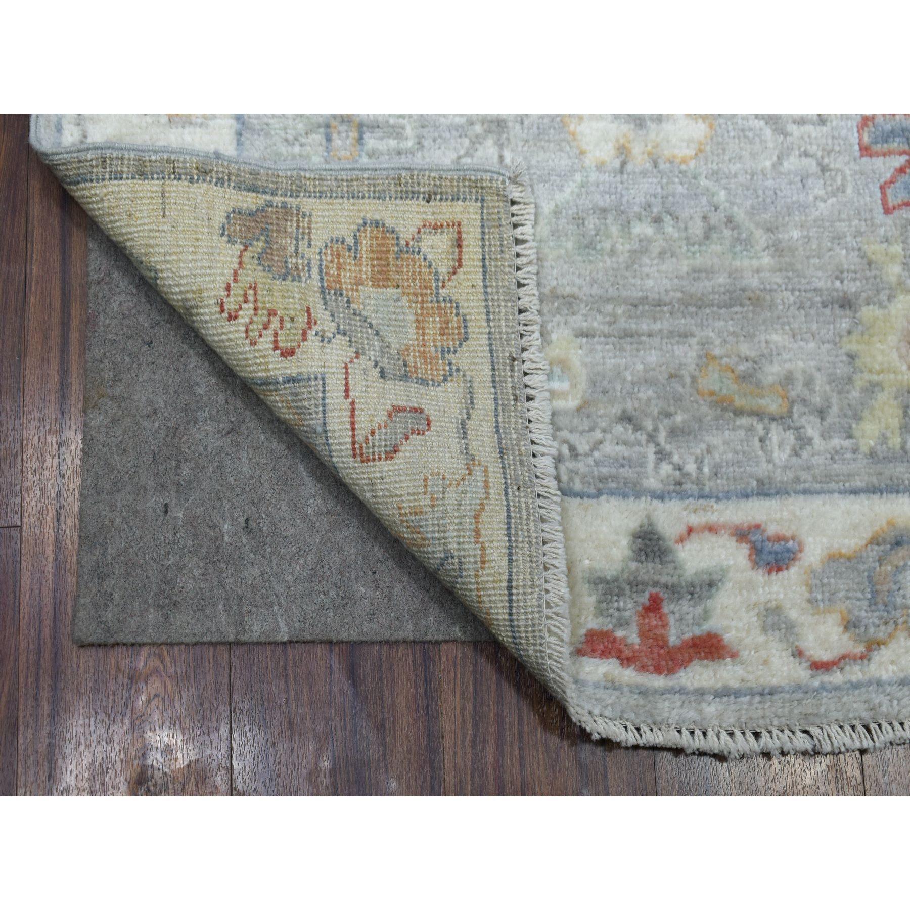 Il s'agit d'un véritable tapis d'Orient, unique en son genre, en laine afghane, gris angora Oushak avec des touches de couleur, noué à la main. Il a été noué pendant des mois et des mois selon des techniques de tissage séculaires par des artisans