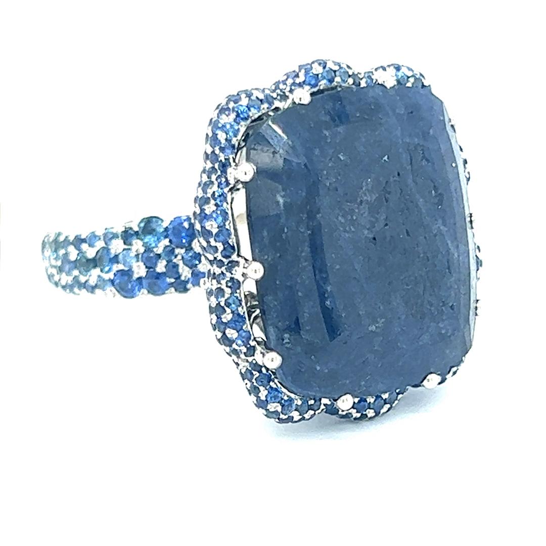 Elevate your elegance with this exquisite 26.91 carat blue sapphire and diamond ring. The centerpiece is a stunning cushion-cut blue sapphire, radiating a deep, mesmerizing hue. Encircled by a halo of sparkling 2.92 carat round diamonds and blue
