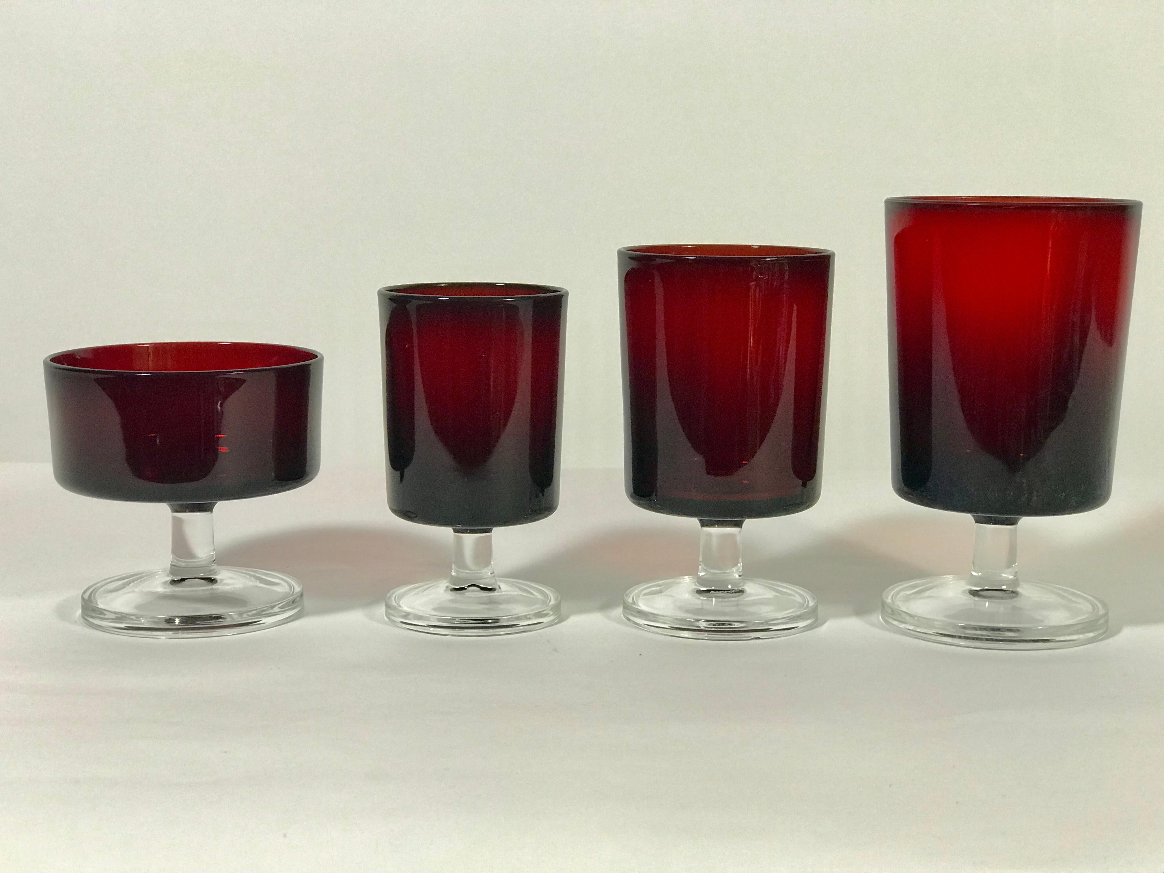 Midcentury 32 piece Luminarc French ruby red glassware/ stemware.. Gorgeous ruby red color with clear stems. Some still retain original Luminarc marking stickers. Elegant minimal design. A lovely addition to any table setting. All pieces marked