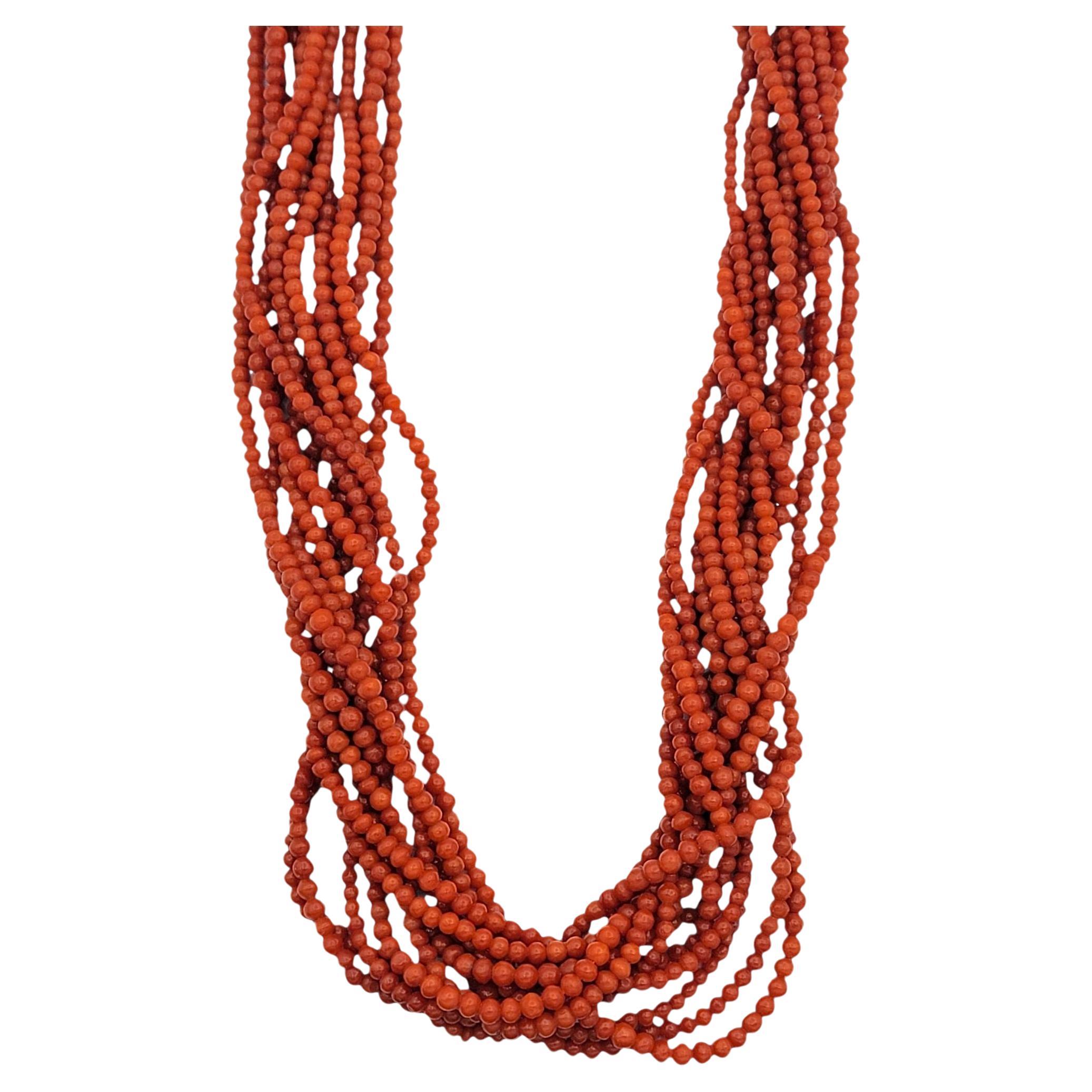 This dramatic red coral beaded necklace makes a commanding statement with its twelve strands of vividly colored beads twisted into an elegant rope design. The strong orange/red hue of the coral brings rich warmth and energy, while the uniform round