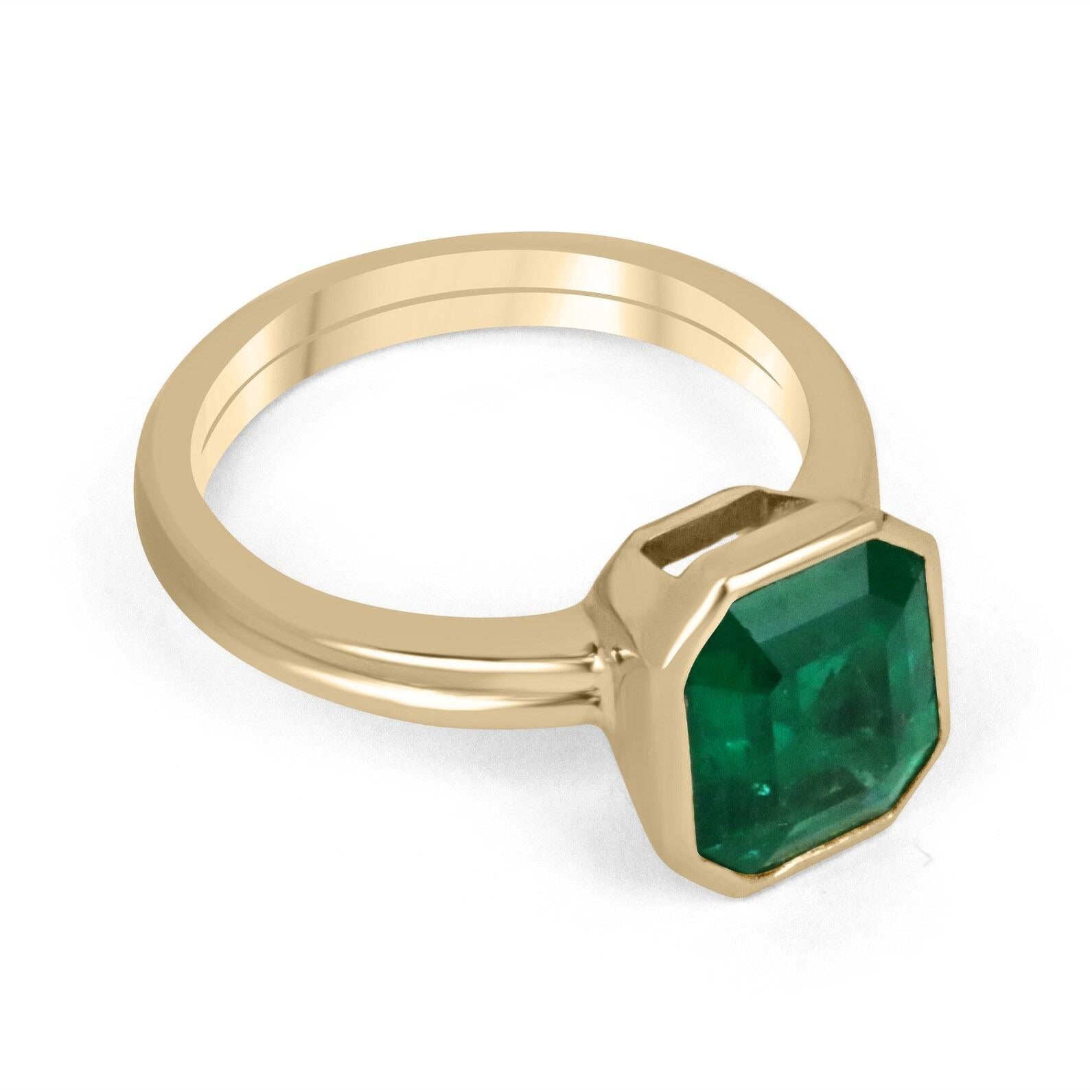 Displayed is a rich dark green Colombian emerald, solitaire, emerald-cut bezel ring in solid 18K yellow gold. This gorgeous solitaire ring carries a full 3.20-carat earth-mined emerald in a sleek and secure bezel setting. The emerald has incredible