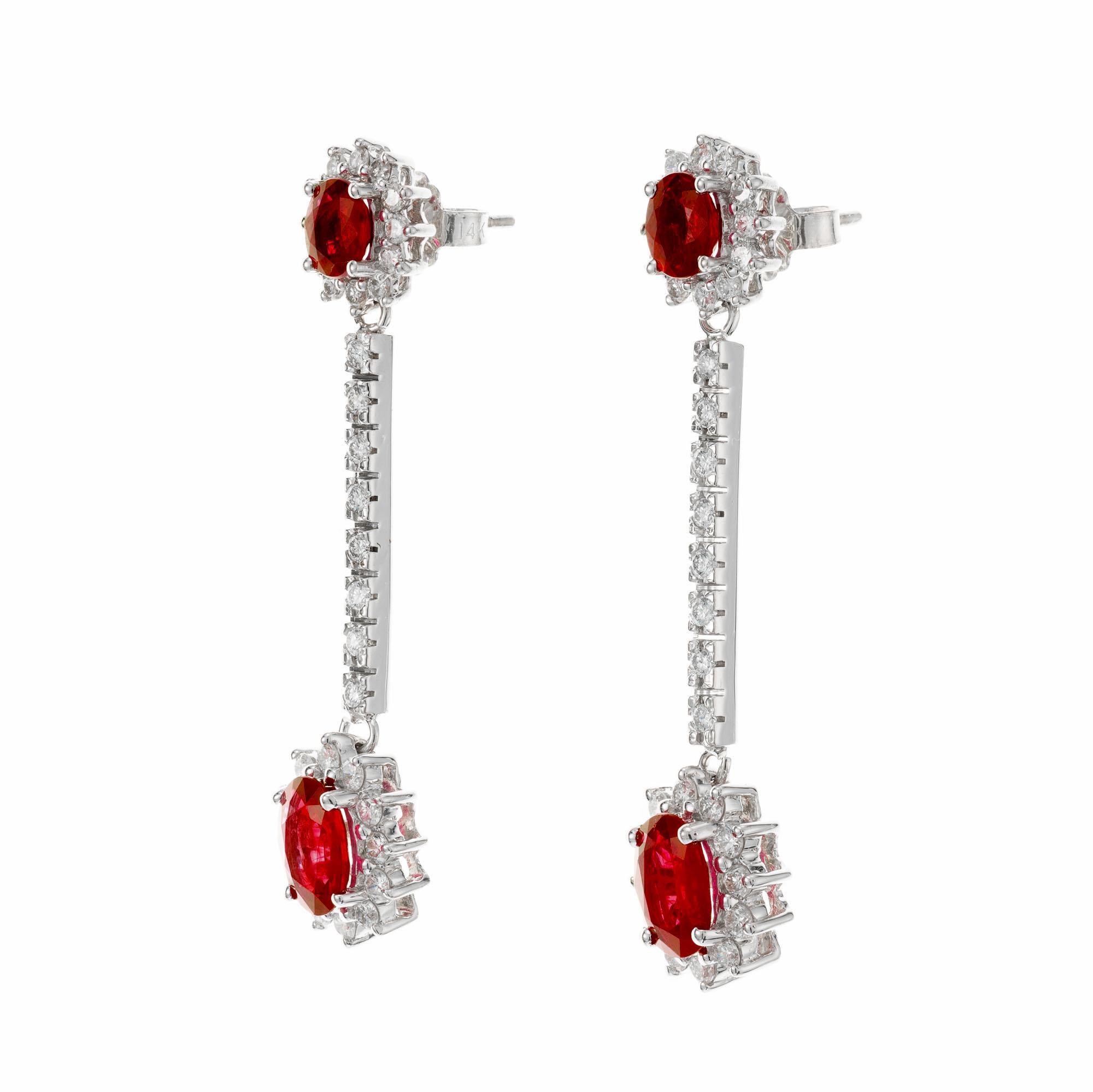 Ruby and white diamond dangle drop earrings. Set in 14k white gold with 4 oval rubies and round full cut accent diamonds. 

4 oval rubies 3.20cts
66 round diamonds approx. total weight .66cts
14k White Gold
Stamped 585 14k
6.0 grams
1 5/8 x 3/8 inch