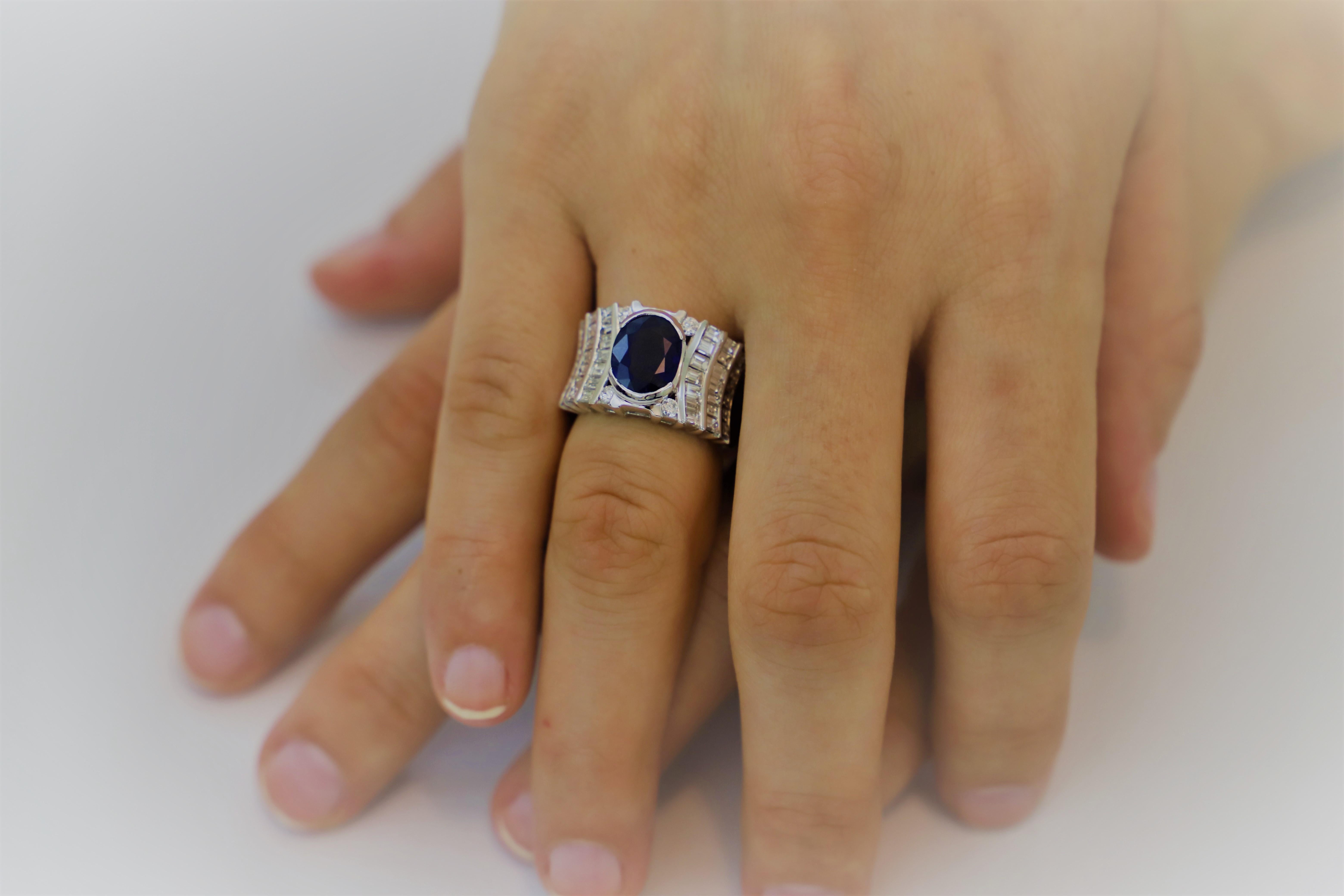 Elegant and Sophisticated Cocktail Ring featuring a 3.20 Carat Oval Sapphire, framed by 4 White Round Diamonds. 
On both sides of the Sapphire, are 3 lines of White Baguette Diamonds, to   enhance brightness and blinking.
White Diamonds are 2.43