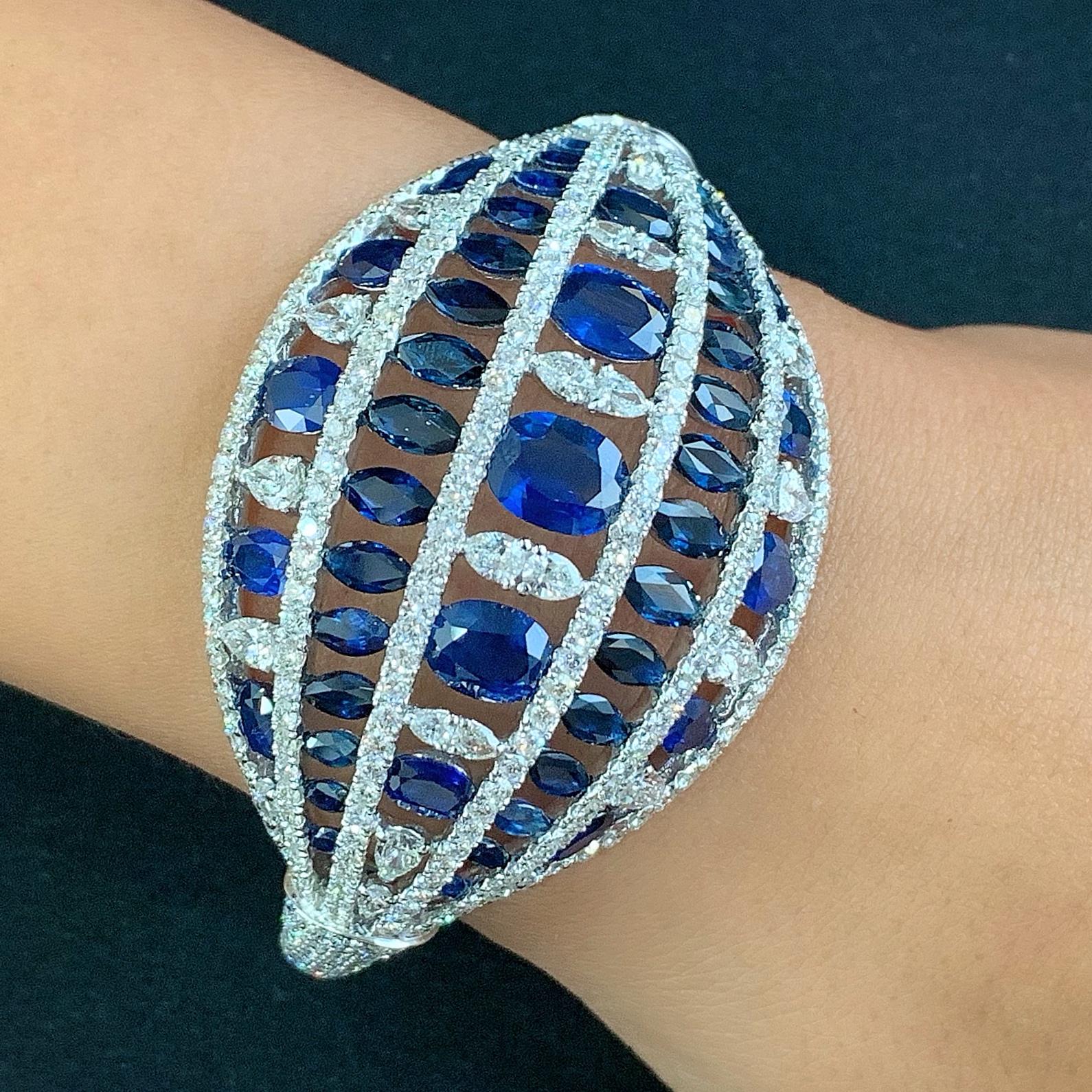 A breathtaking dome of royal blue oval and marquise sapphires (totaling 21.10 carats) is illuminated with over 350 dazzling pear-cut and brilliant-cut diamonds (totaling 10.95 carats).  Handcrafted in 18K white gold, this cuff bangle is the perfect