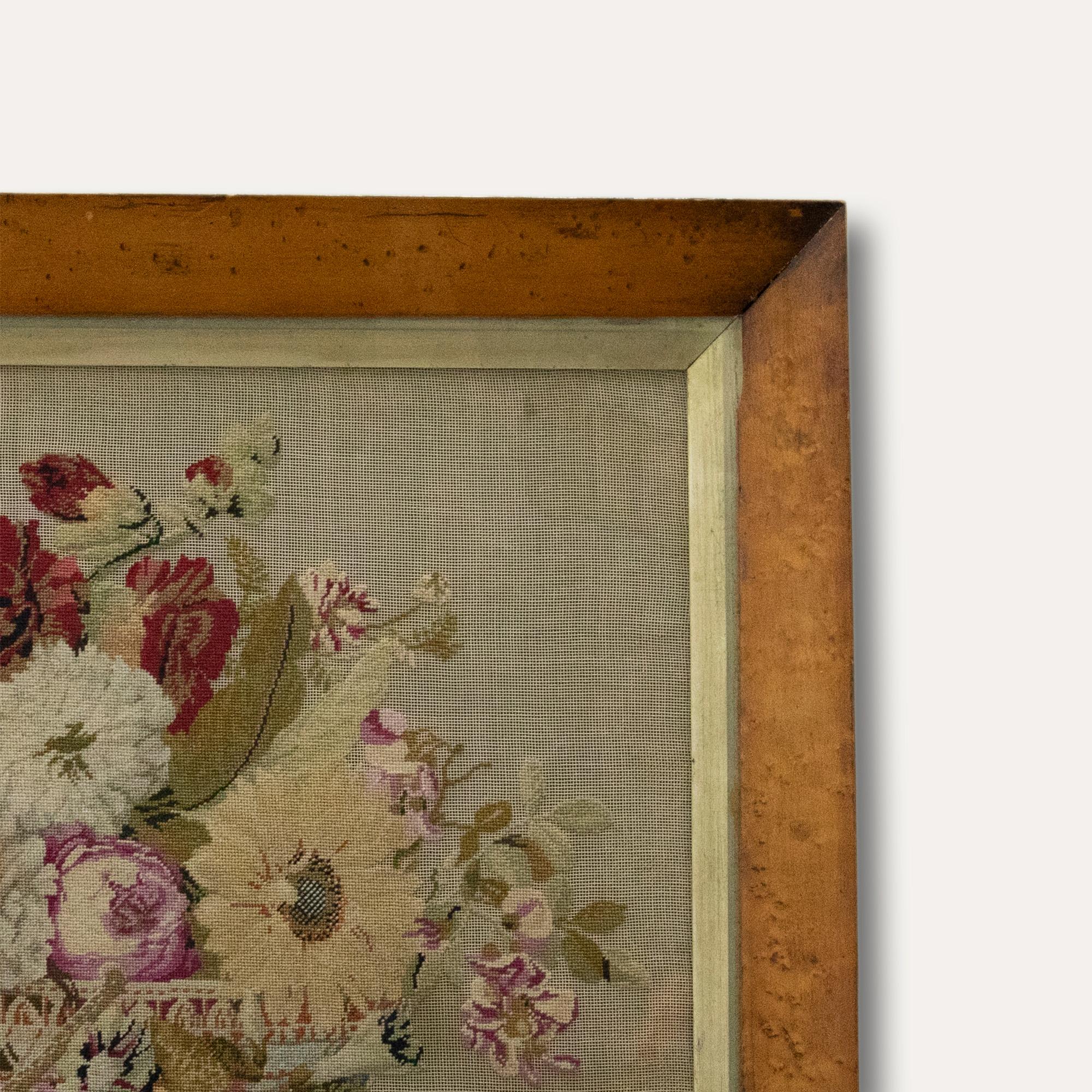 An exquisite needlework picture depicting a still life of garden flowers inside a pierced china basket. Beautifully mounted in a period bird's eye maple frame with internal slip and glazing. On linen.