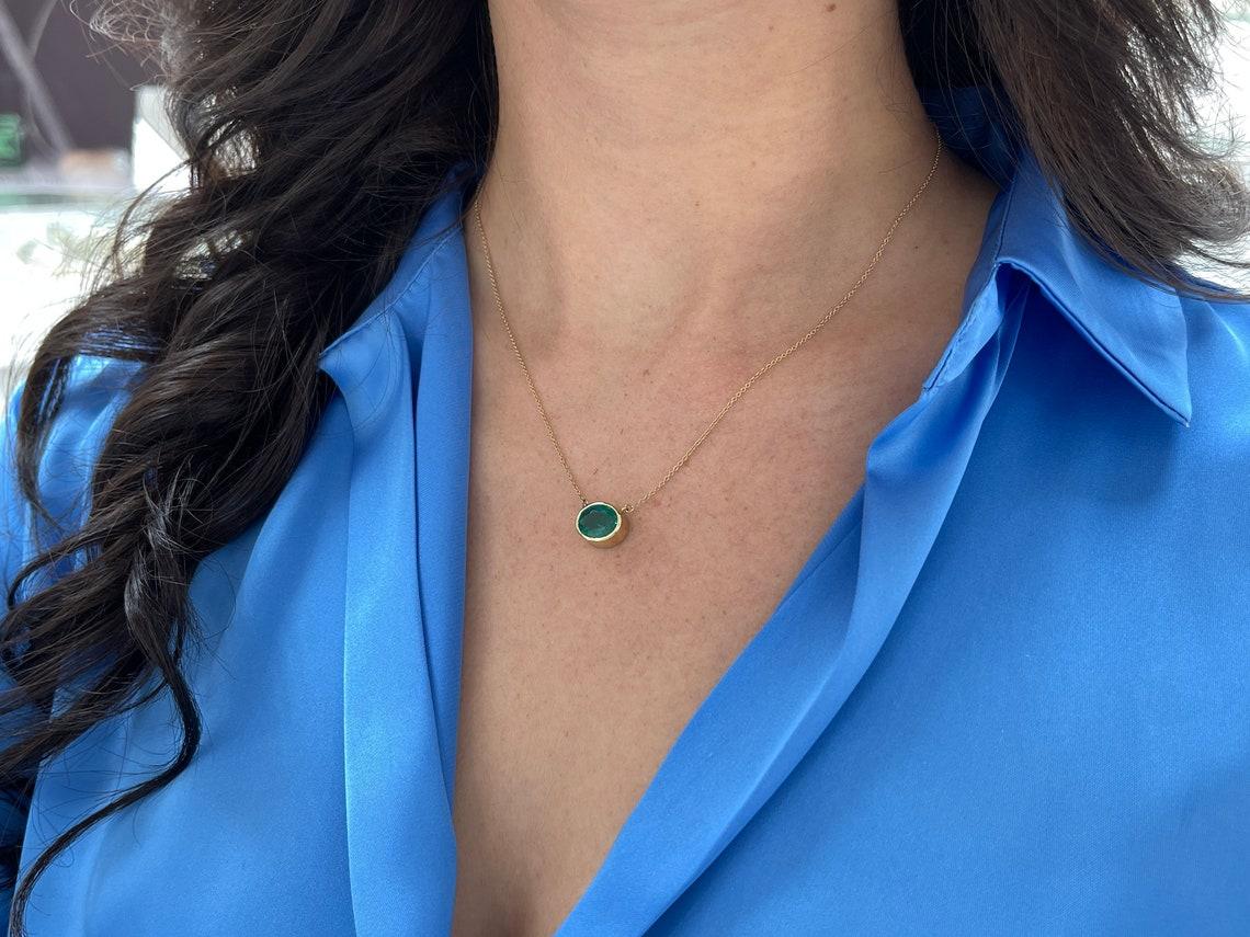 Introducing a captivating solitaire emerald necklace, adorned with a breathtaking 3.20-carat oval cut emerald. Set horizontally in a full bezel setting, the emerald showcases a deep, rich green color, with semi-transparent clarity and a delightful