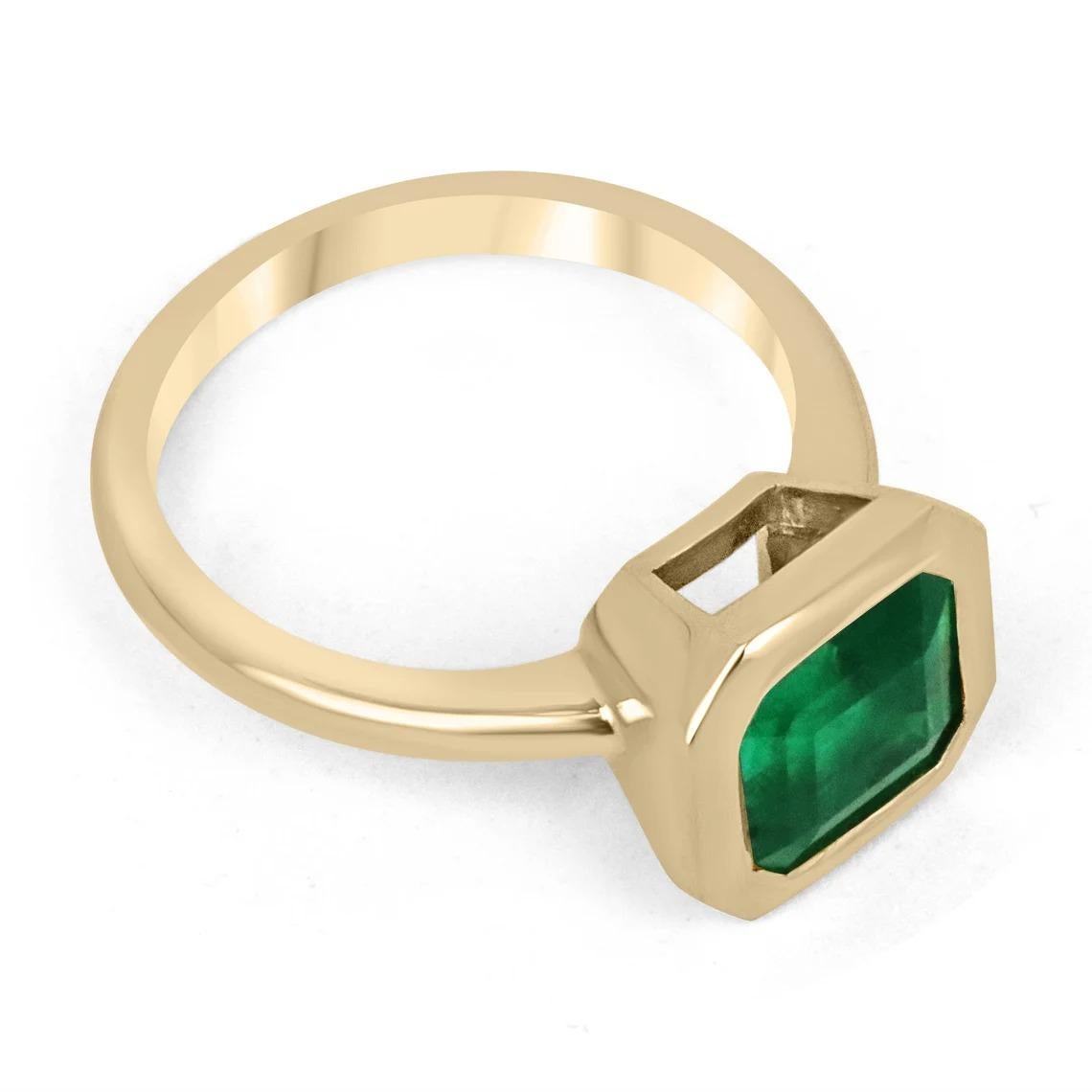 Displayed is a rich dark green AAA+ top-of-the-line Colombian emerald, solitaire, emerald-cut bezel ring in solid 18K yellow gold. This gorgeous solitaire ring carries a full 3.20-carat earth-mined emerald in a sleek and secure bezel setting. The