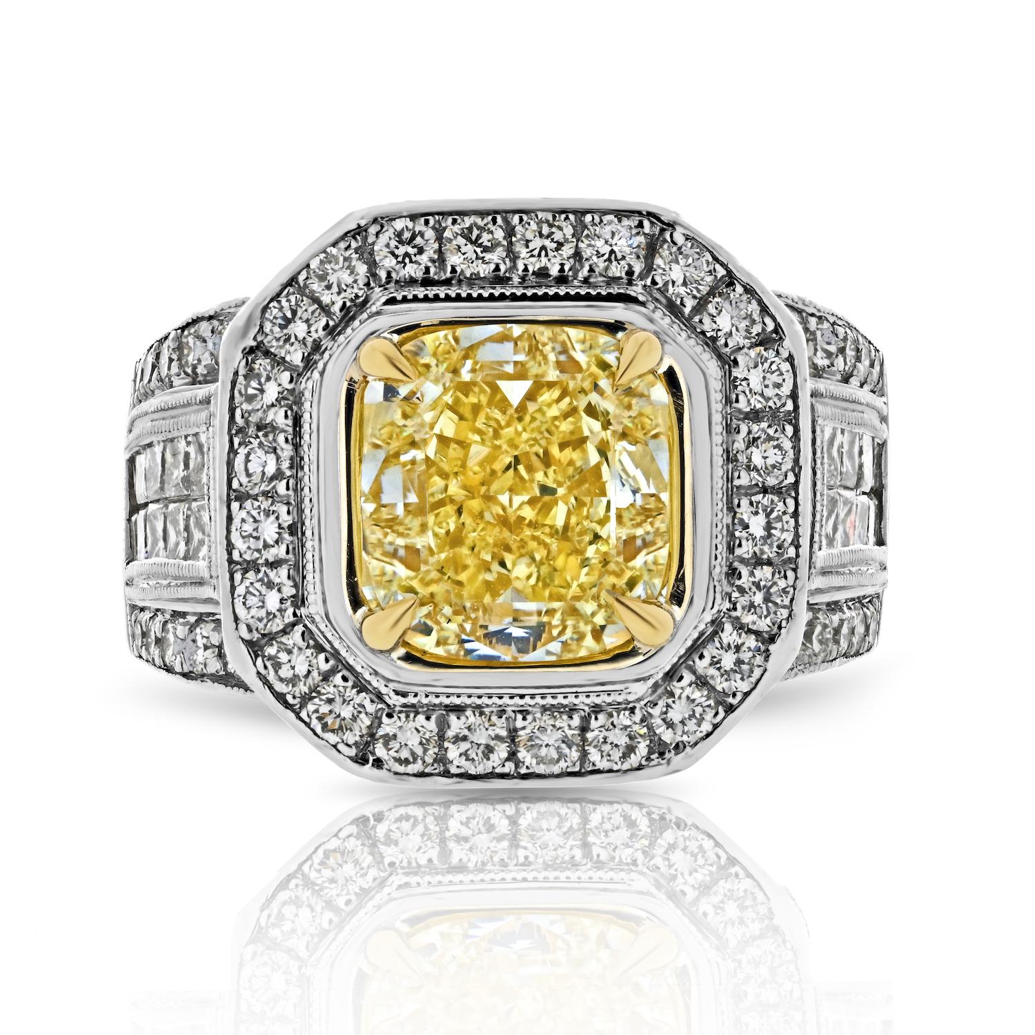 Embrace the allure of this remarkable 3.20ct Fancy Yellow Intense Cushion Cut Diamond Engagement Ring. Gracing the center stage is a splendid 3.20-carat cushion-cut diamond, radiating in the striking Fancy Yellow Intense color, and exhibiting