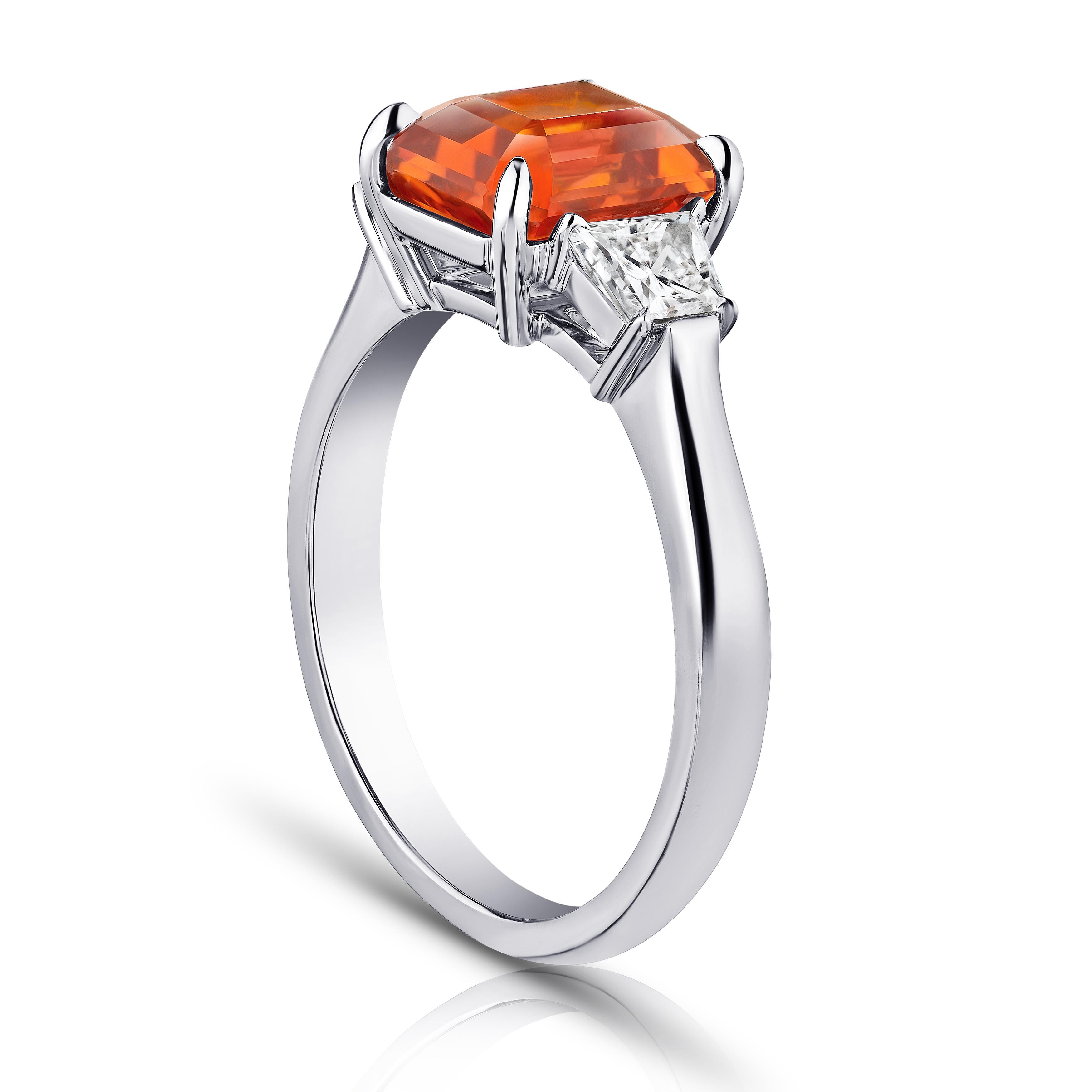 3.21 carat emerald cut orange sapphire with tapered radiant cut diamonds .63 carats set in a platinum ring. Ring is currently a size 7. Resizing to your finger size is included.