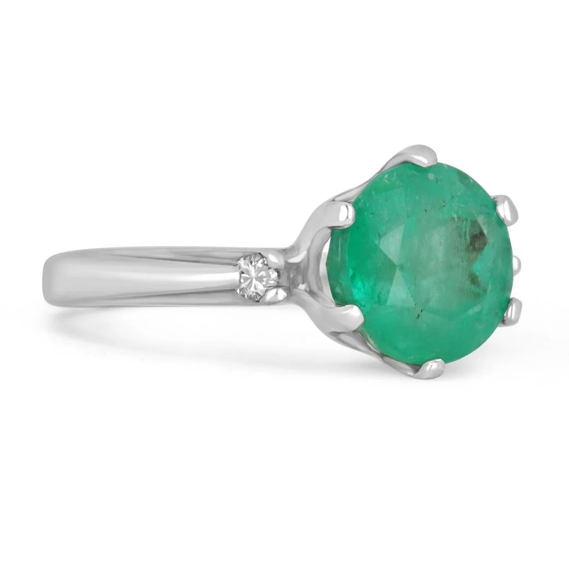 A simple, emerald and diamond three stone. The center stone carries a full, 3.19-carat round cut Colombian emerald. The stone displays a beautiful medium yellowish-green color and good eye clarity. The gemstone is slightly opaque from within, yet