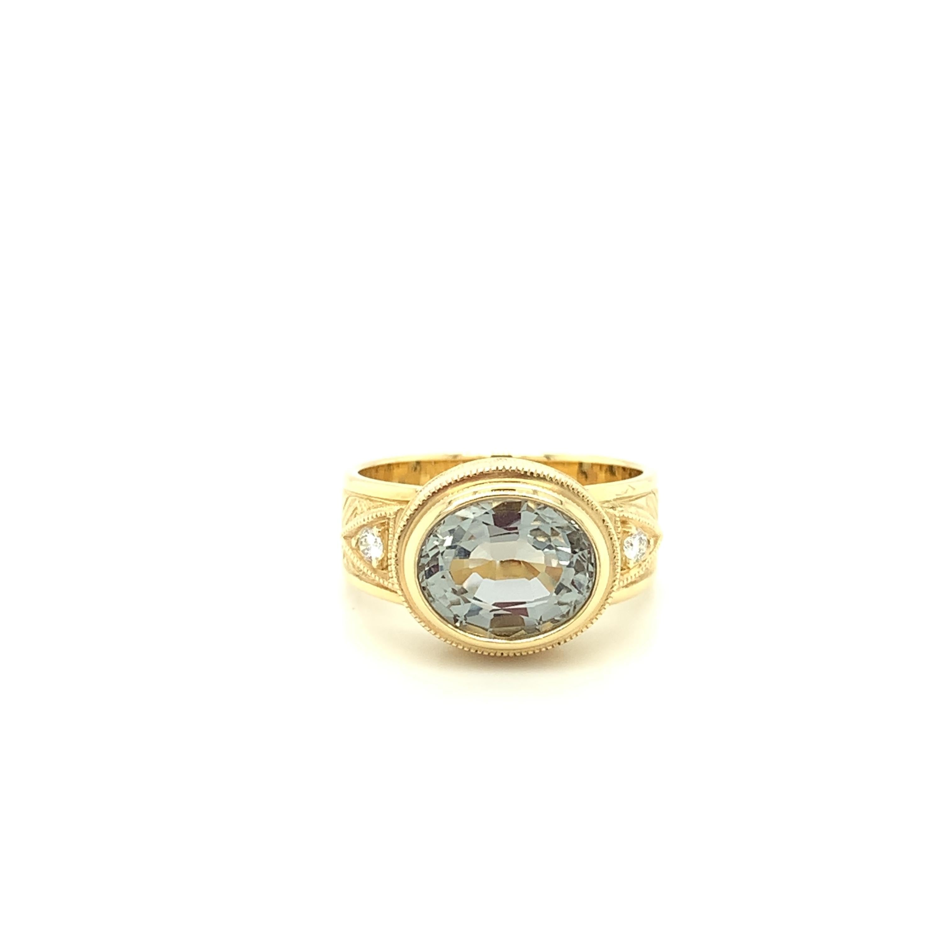 This handmade 18k yellow gold ring features a crystalline silver gray topaz oval that has been set 