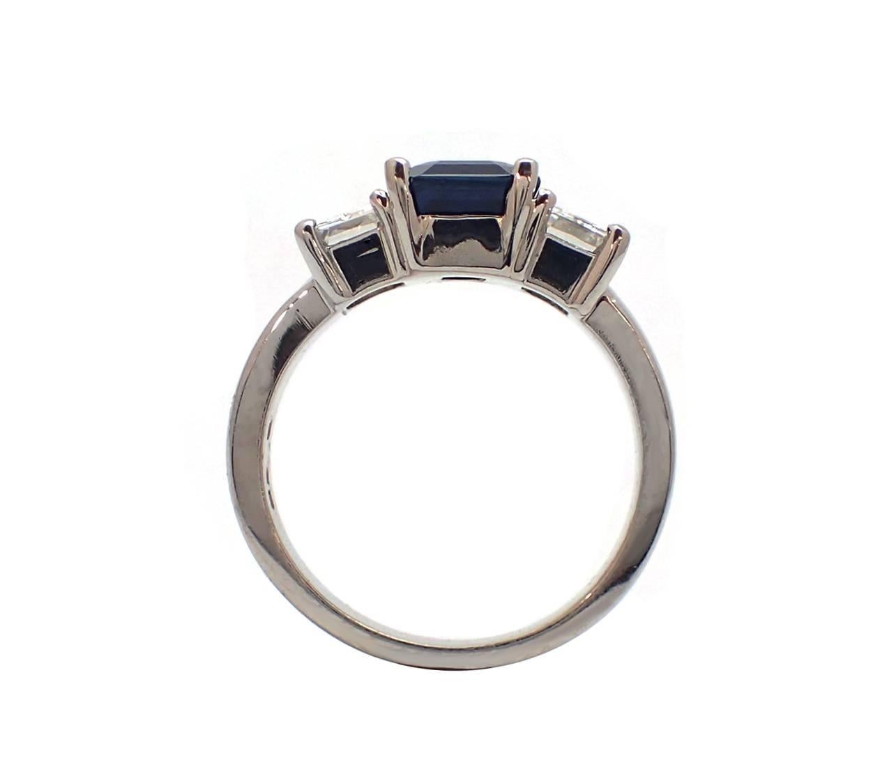 This beautiful platinum ring features a stunning 3.24ct emerald cut sapphire set between two emerald cut diamonds totaling 1.53ct. Wear this ring for a classic, timeless look with a pop of color! Finger size 7 1/4 (Sizable).  Medium-medium dark blue