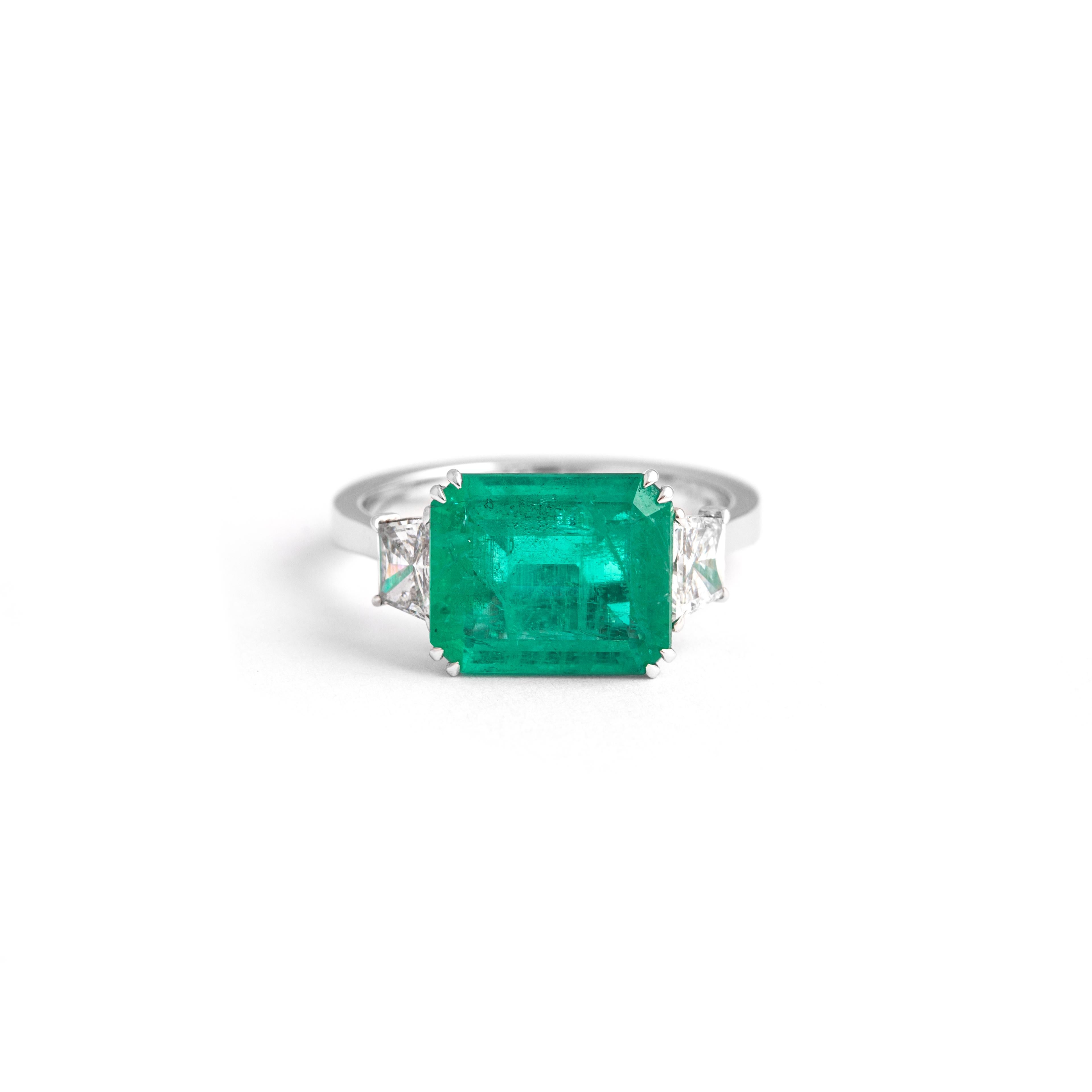 Ring mit 3,25 Karat kolumbianischem Smaragd, GRS-zertifiziert, geringfügig bis mäßig, flankiert von einem Paar Diamanten im Trap-Brillantschliff mit 0,67 Karat E/VS, 3,9 Gramm. 
WG
Gewicht: 4,83 Gramm.
Größe: 54