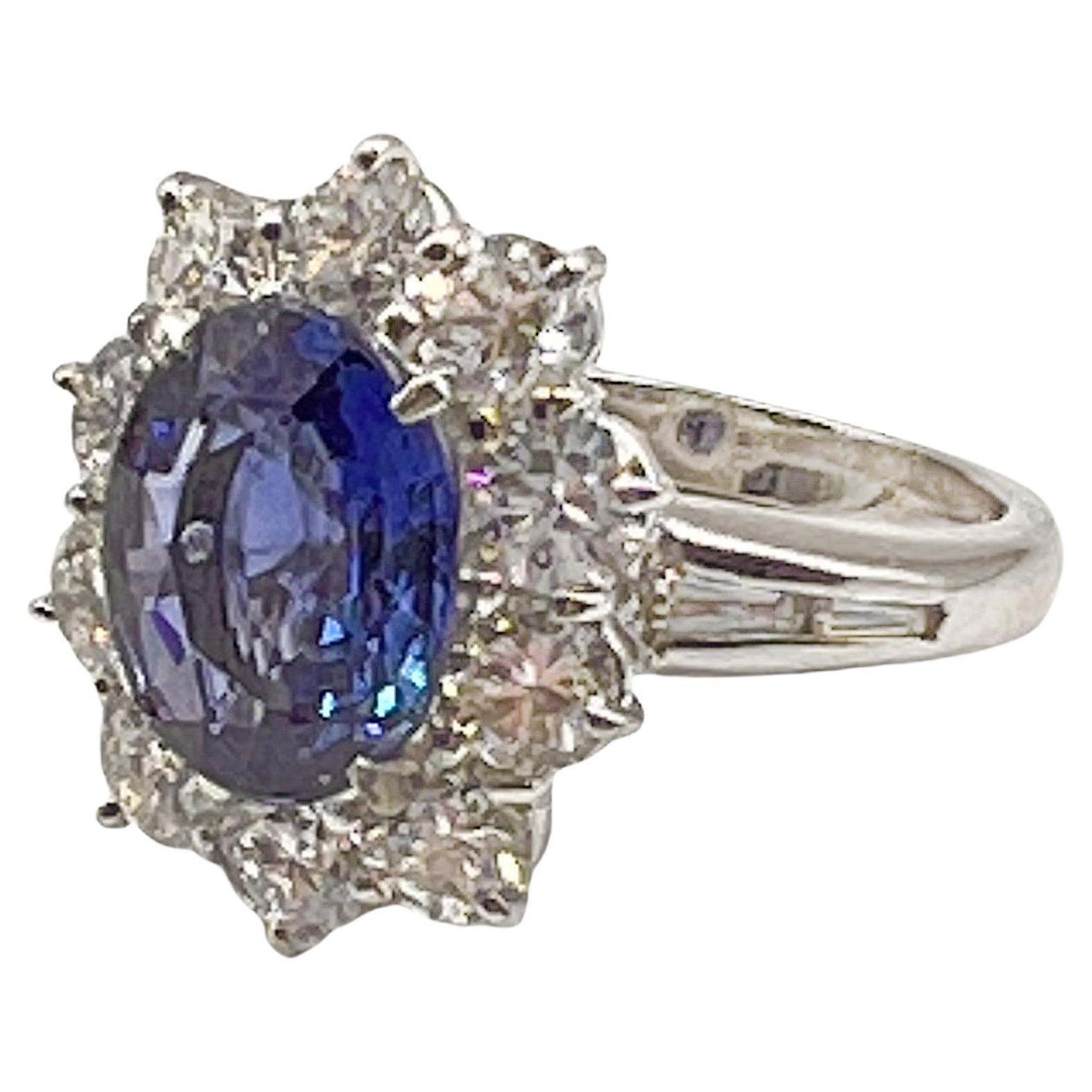 Beautiful cornflower blue natural sapphire weighing 3.25 carats set in four-prongs in a handmade platinum mounting.  The sapphire is surrounded by ten near-colorless round brilliant-cut diamonds with four baguette-cut diamonds inset on the top sides