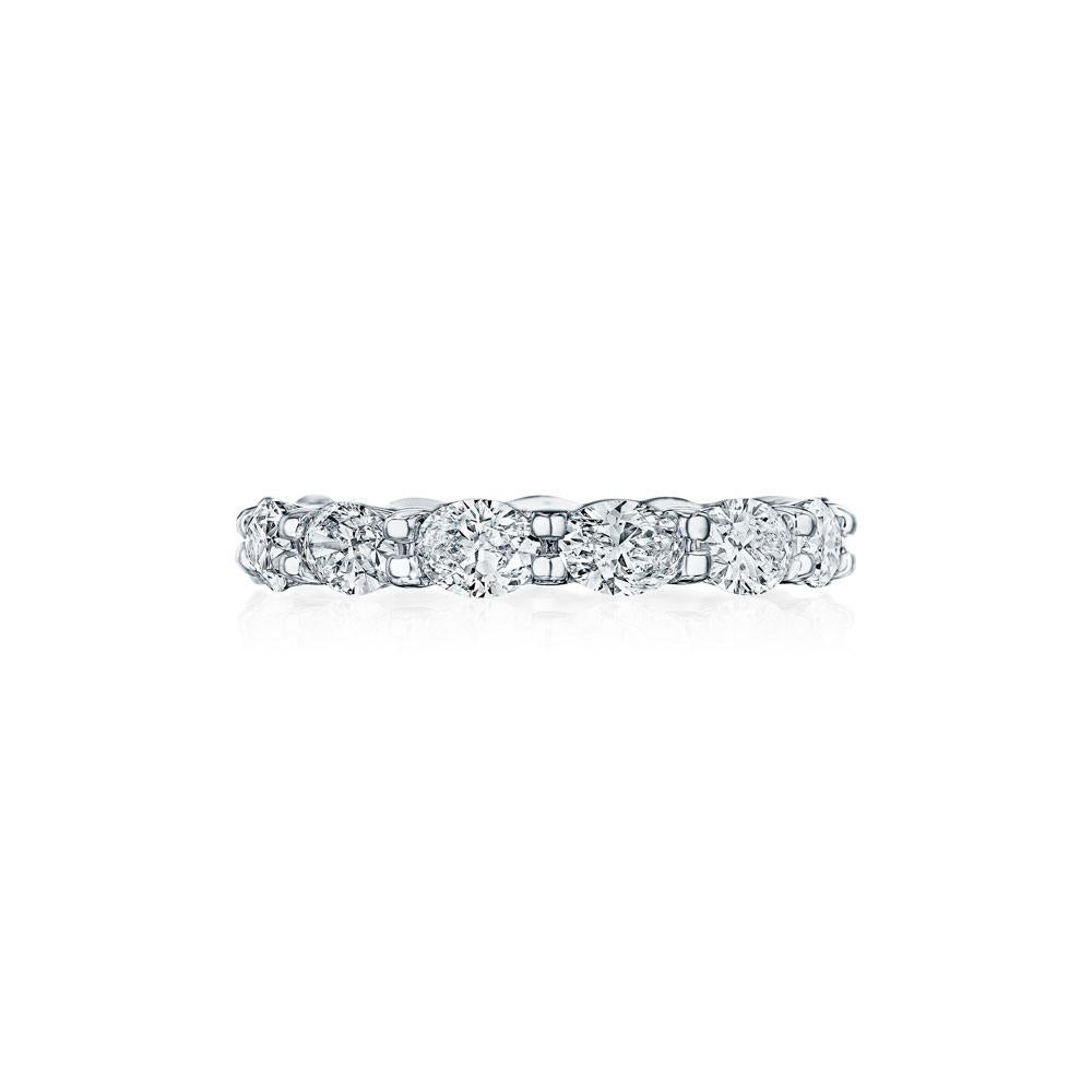 Crafted in 18KT gold, this band is made with 13 oval cut diamonds which encircle the finger, and has a combining total weight of approximately 3.25 carat. The diamonds are set east to west in a shared prong setting. Worn beautifully on its own or