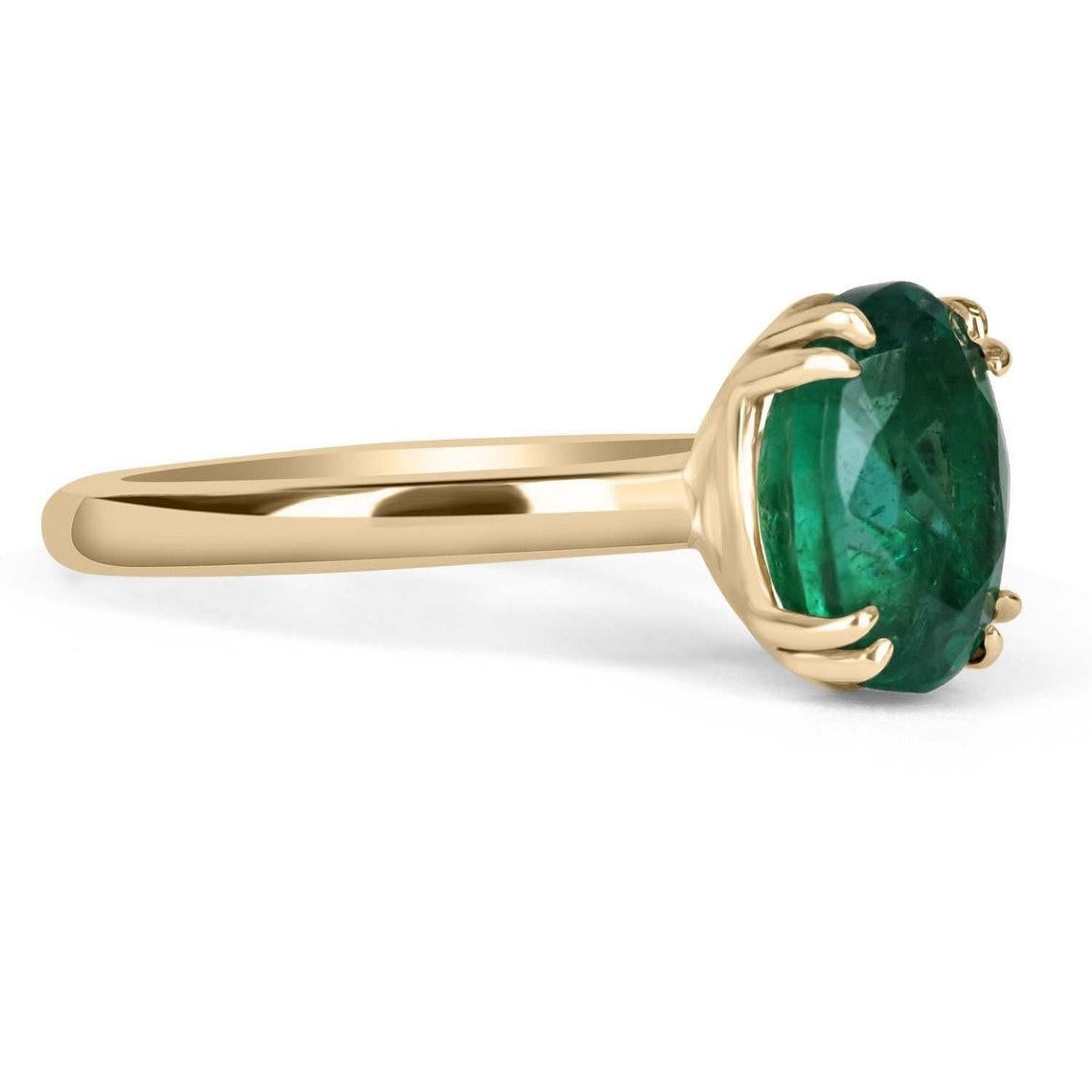 Displayed is a custom emerald solitaire oval-cut engagement/right-hand ring in 14K yellow gold. This gorgeous solitaire ring carries a 3.25-carat emerald in a 4, double prong setting. The emerald has very good clarity with minor flaws that are
