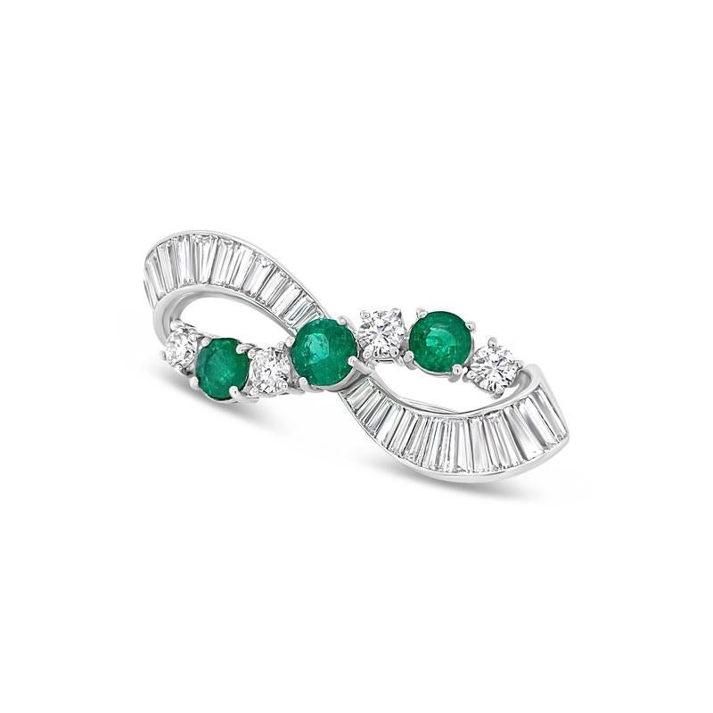 A beautiful pin featuring 3.25 carat total weight in prong set round brilliant diamonds and channel set tapered baguettes and 1.45 carat total weight in prong set round emeralds set in 14 karat white gold.  This can be worn many different ways.  It