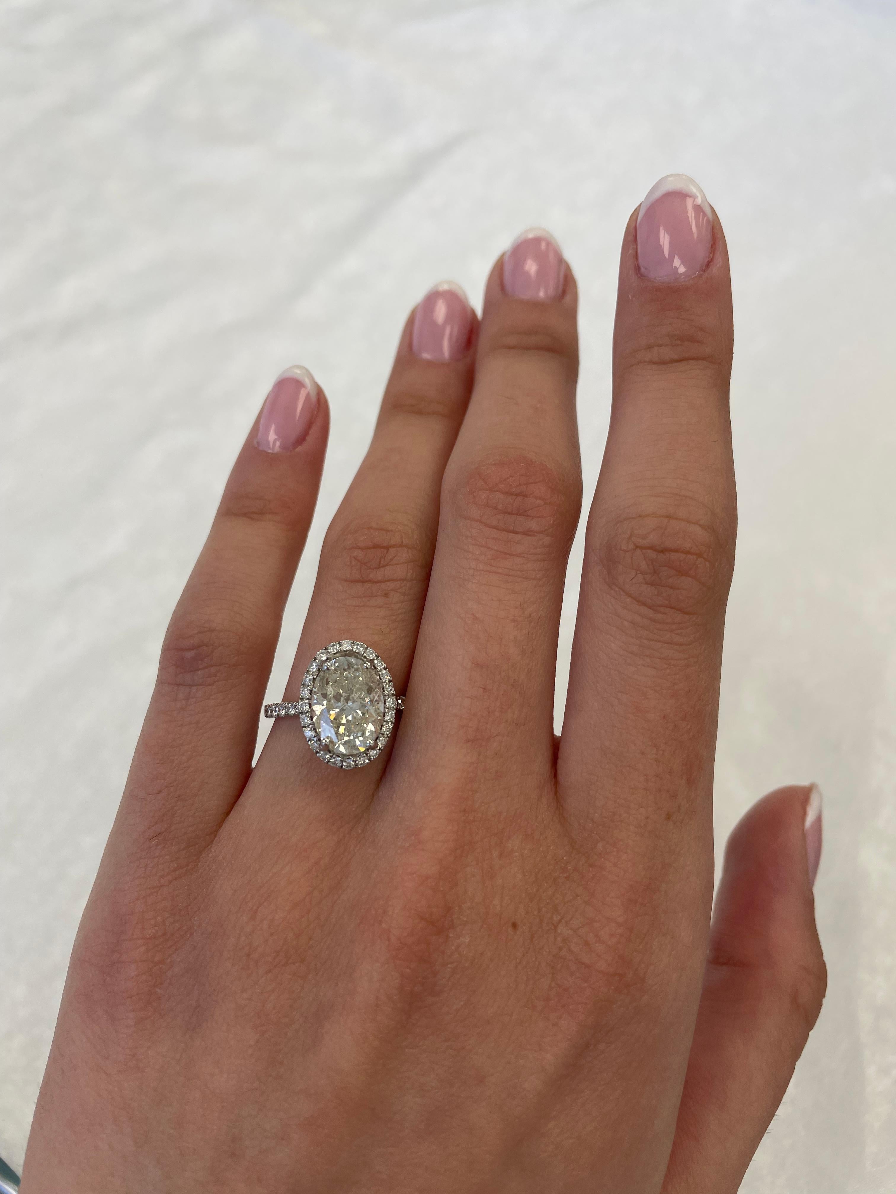 Classic diamond with halo engagement ring with diamonds down the shank.
3.82 carats total diamond weight.
3.26 carat oval diamond, EGL certified I/J color grade and SI3 clarity grade. Complimented by 0.56 carats of round brilliant diamonds,