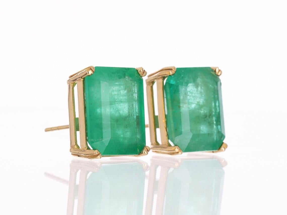 A classic and massive pair of emerald-cut green natural Colombian emerald gold studs in 18K Gold. These earrings feature two lively, natural Colombian emeralds that are handset in a single four-prong setting. These stones were sourced by the best