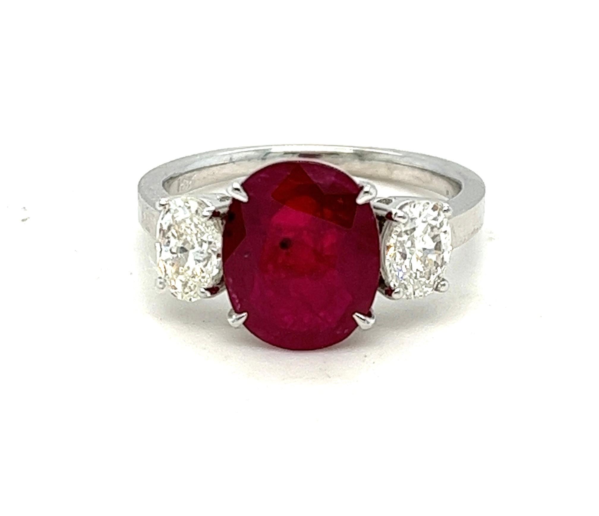 Offered here is a classic 3 stone engagement ring, simple yet so elegant.
Featuring a large 3.27 carat oval dark red natural ruby flanked with natural earth mined oval diamond on each side of the shank, mounted in solid 18 karat white gold ring, in