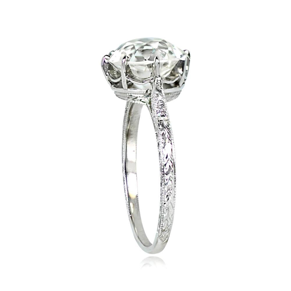 This exquisite Art Deco era engagement ring features a 3.29 carat old European cut diamond, K color, and VS1 clarity, elegantly set in prongs. The hand-engraved shank leads to shoulders set with additional old European cut diamonds weighing