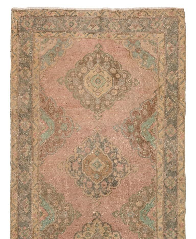 A vintage Turkish runner rug in soft colors. It was hand-knotted in the 1960s with low wool on cotton foundation and features a multiple medallion design. It is in very good condition, professionally-washed, sturdy and suitable for areas with high
