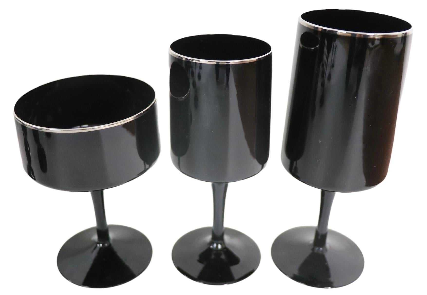 Exceptional large set of stemware by noted maker Lenox, in the Venture pattern. The glasses are black glass with platinum band trim at the top rim. The set consists of three sizes as follows:
 10 Saucer Champagne Glasses 5 H x 4 Dia.
 11 Wine