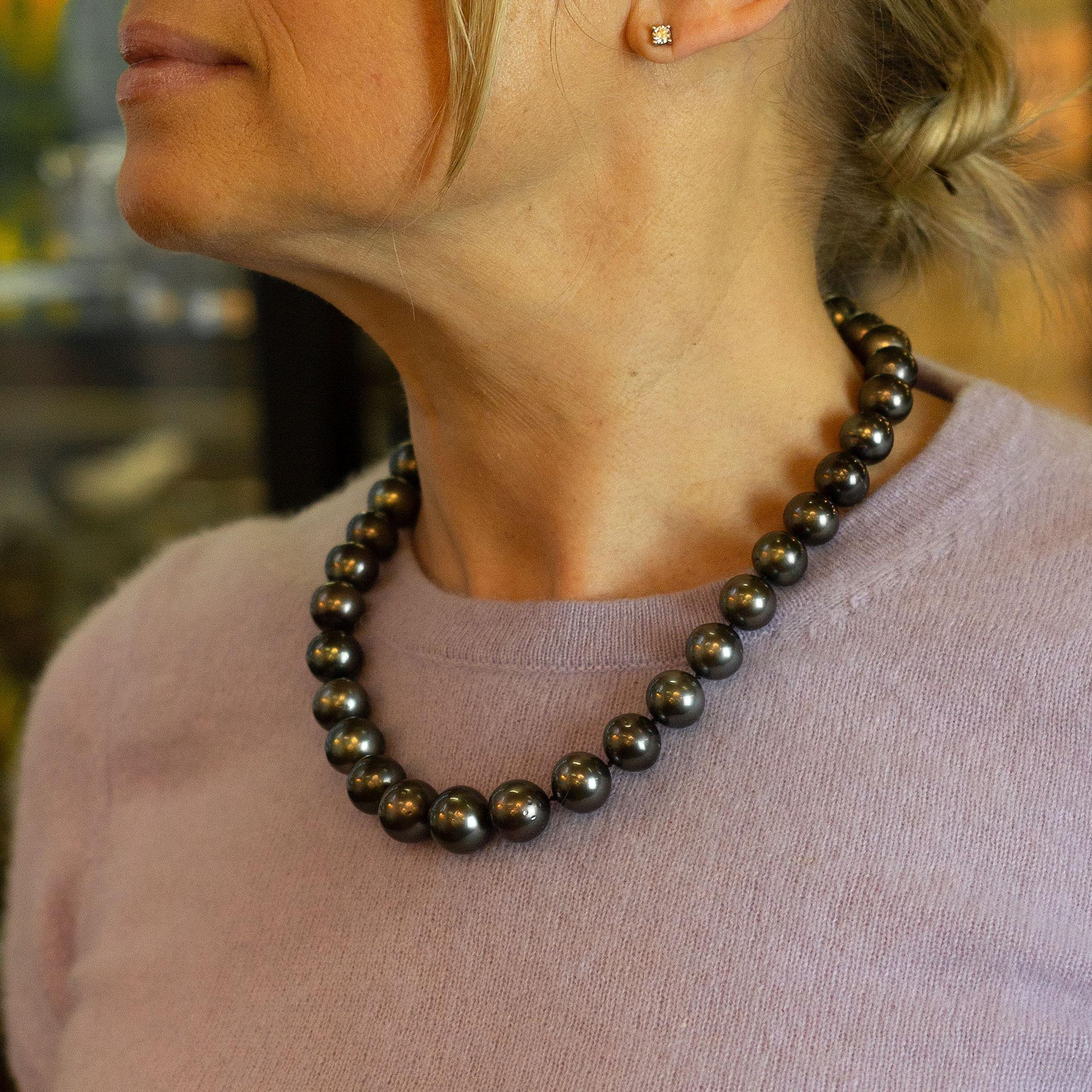 A fine strand of cultured Tahitian pearls finished with a scalloped 14 karat white gold plunger style bead clasp. The strand has been recently restrung and each pearl is individually knotted to ensure they are secure when worn. The pearls are