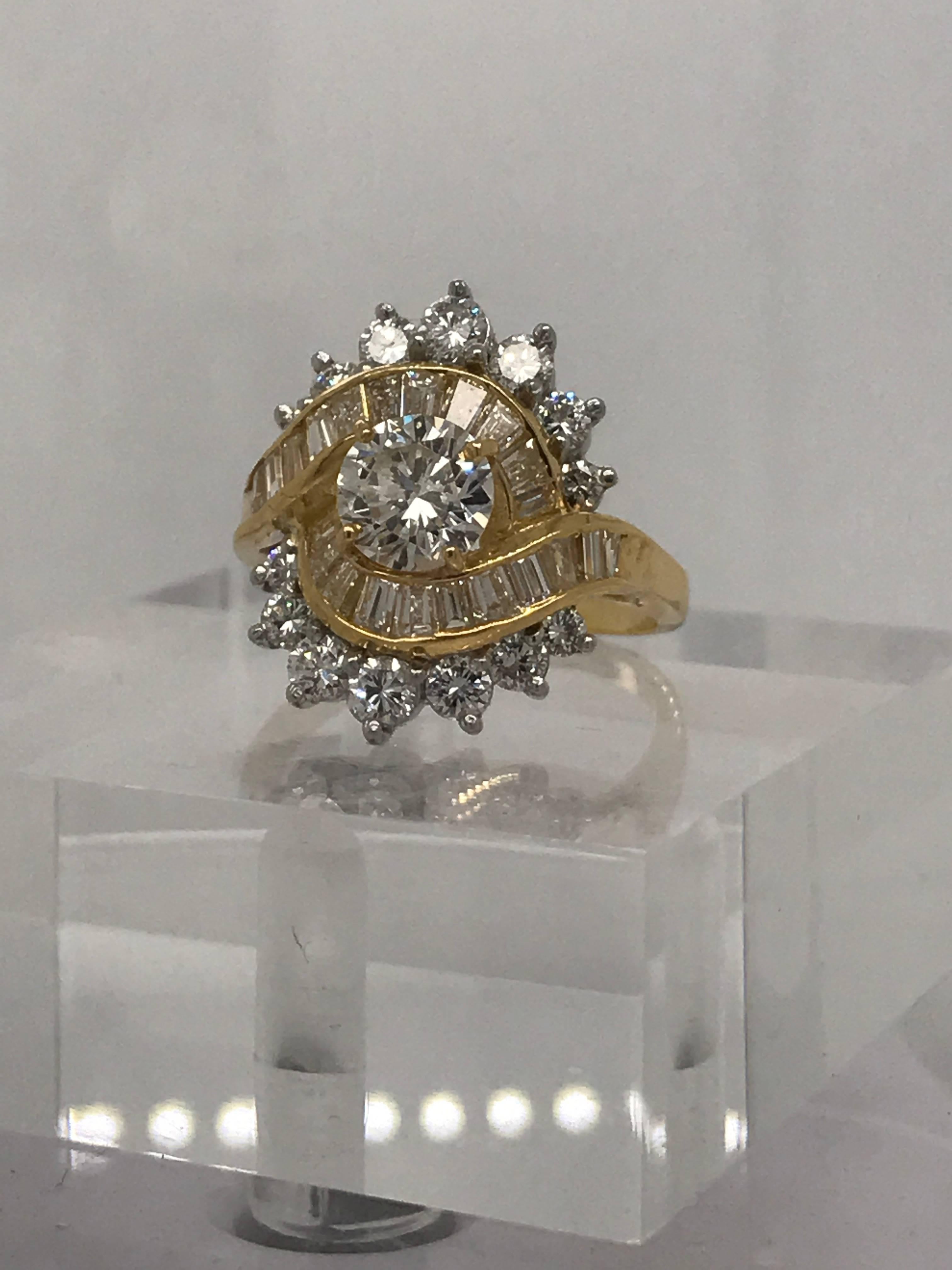 A beautiful ring with multiple different cuts of high-quality diamonds. The largest center stone weighs .99 carat and is graded a J color SI2 clarity. 14 more round accent diamonds total 1.10 carats and surround 22 baguette cut diamonds weighing