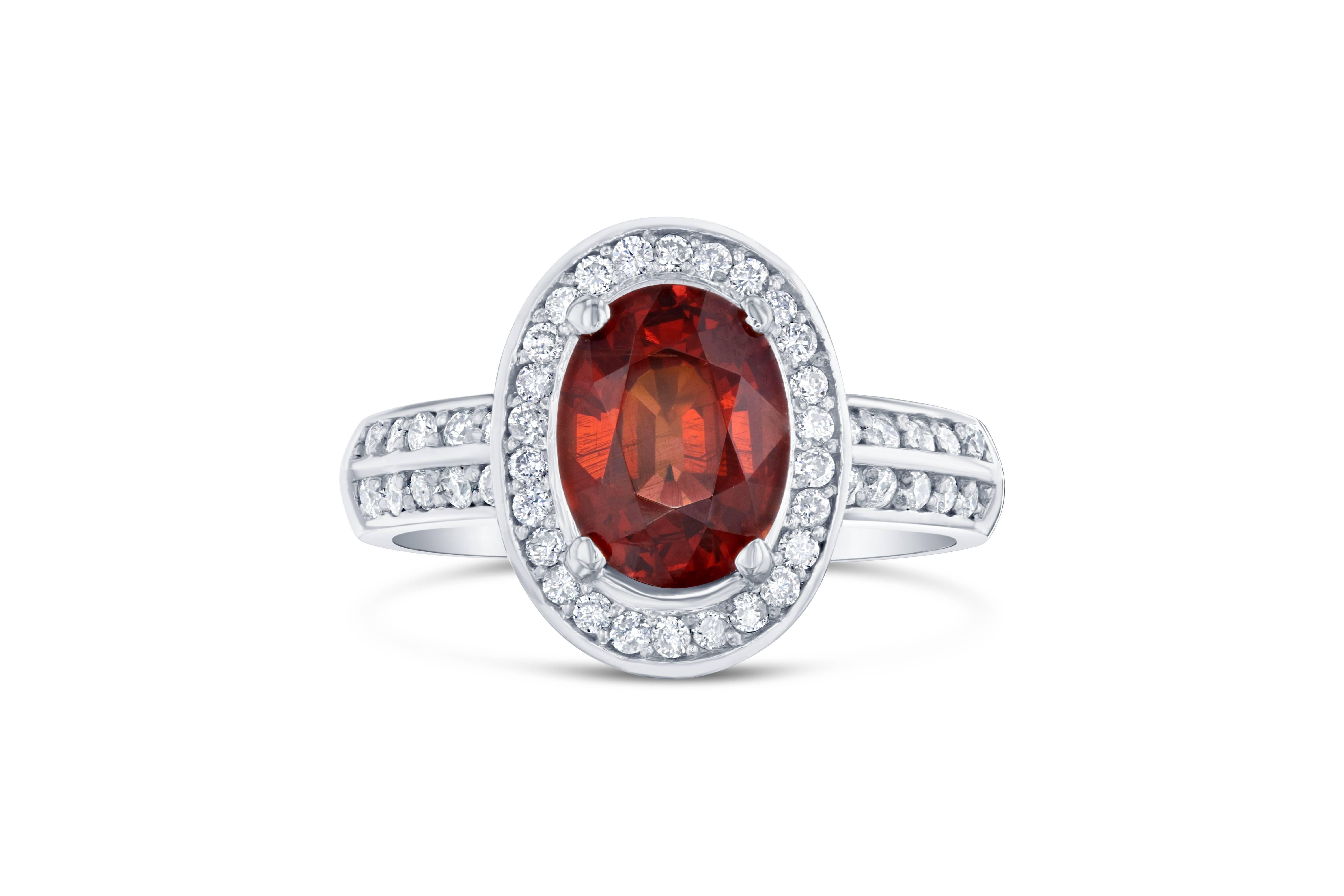 This simple everyday ring has a gorgeous 2.87 Carat Oval Cut Spessartine Garnet. Spessartines are natural gemstones. The ring is surrounded by a halo of 46 Round Cut Diamonds surrounding the stone and on the shank of the ring that weigh 0.45 carat.