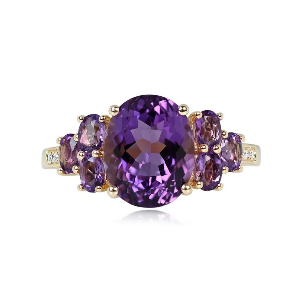 An exquisite ring featuring a striking oval-cut amethyst weighing 3.32 carats at its center, flanked by additional amethysts on each shoulder. The semi-mount is crafted from lustrous 18K yellow gold, adding a touch of warmth to the piece.