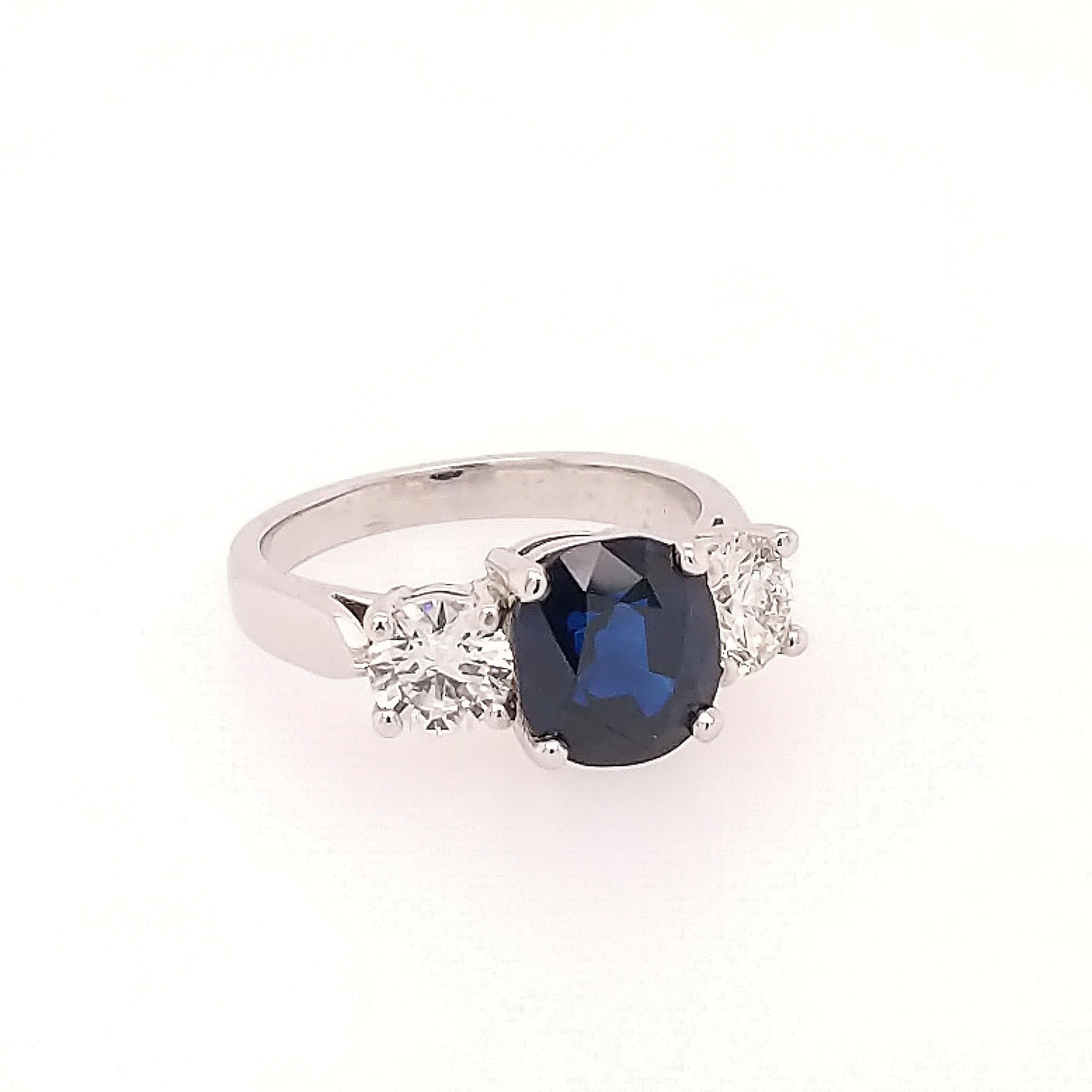 This classic 3 stone sapphire and diamond ring is crafted in 18k white gold featuring (1) oval sapphire weighing 3.32ct with a medium dark blue color. The center stone is flanked by (2) round diamonds weighing 1.03cttw with a color of H/I and a