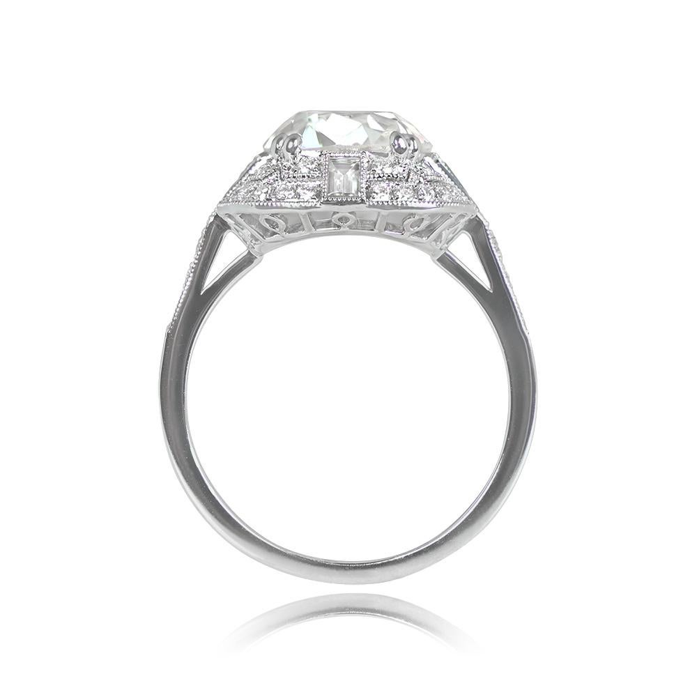 This remarkable geometric ring showcases a 3.33-carat antique cushion-cut diamond with M color and SI2 clarity. Encircling the center stone are two rows of round brilliant-cut diamonds, forming a halo. Additionally, three baguette-cut natural