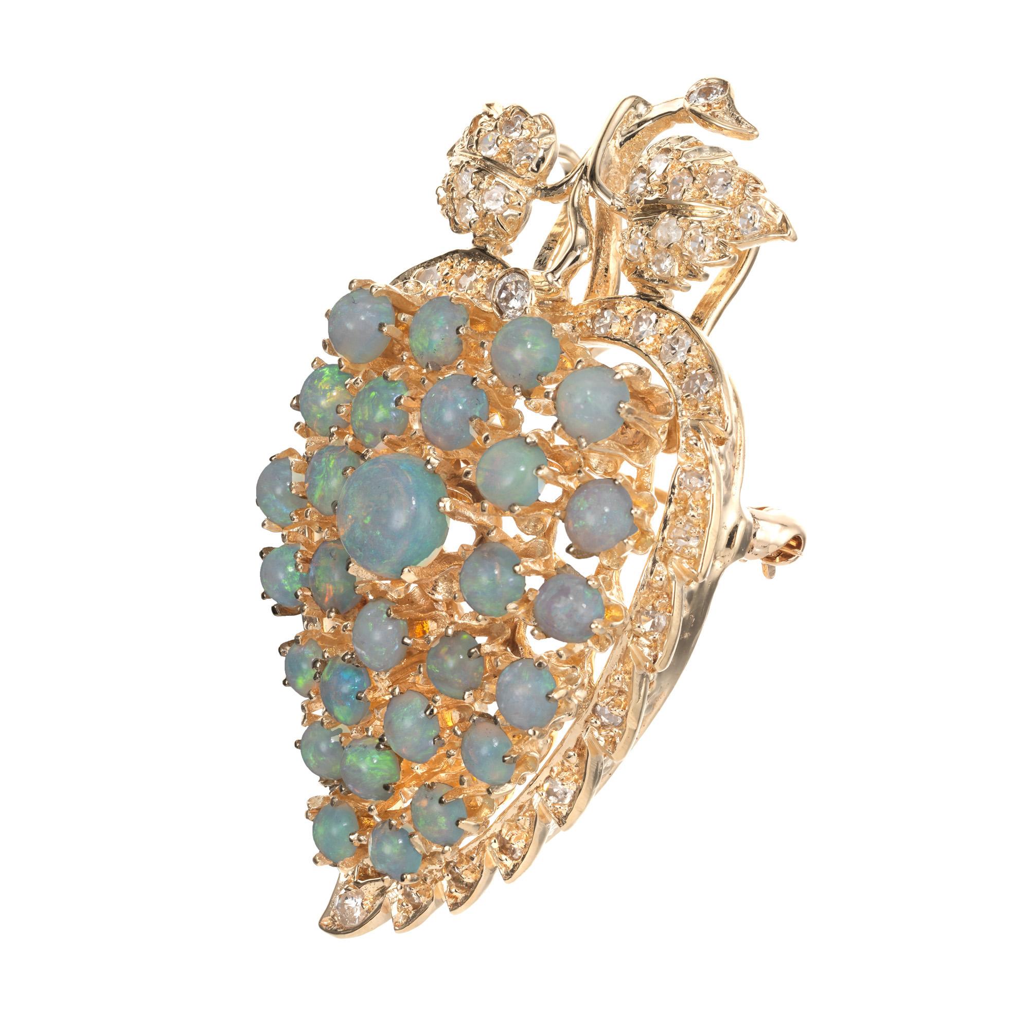 Beautiful 1960's opal and diamond brooch. 28 varying in size, round bluish green fiery cabochon opals set in a 14k yellow gold grape leaf design that can be worn as a brooch or pendant. The opals are accented with 43 round cut diamonds.  

28 bluish