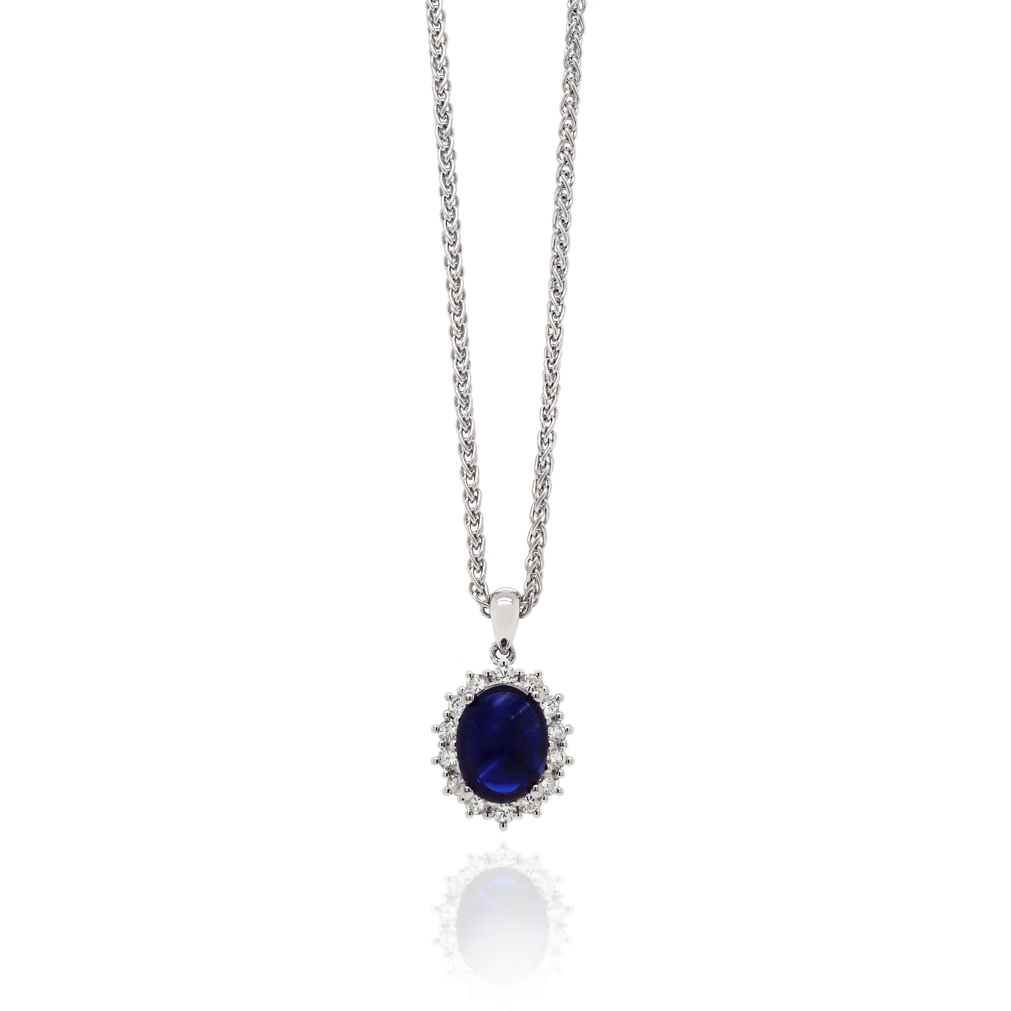 A beautiful pendant featuring a rich blue oval cabochon sapphire in a four claw open back setting weighing 3.37ct. The sapphire is further surrounded by 14 claw set round brilliant cut diamonds weighing a total of 0.49ct all mounted in 18ct white