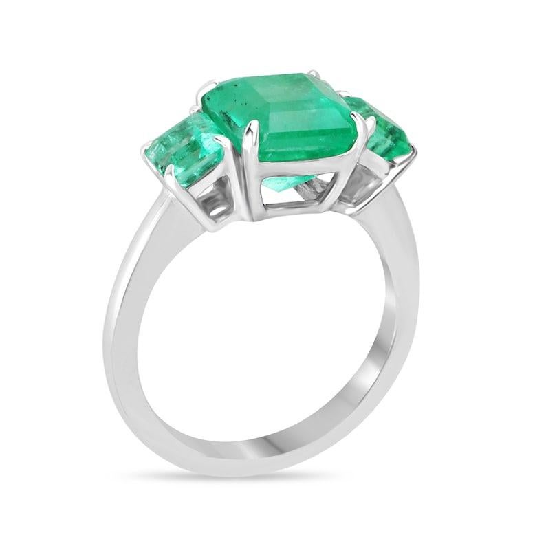 Unveil unparalleled elegance with our Colombian emerald trilogy ring, boasting a mesmerizing 2.50-carat asscher-cut centerpiece flanked by two smaller emeralds, creating a perfect three-stone ensemble. The bright, vivid green hue of the emeralds