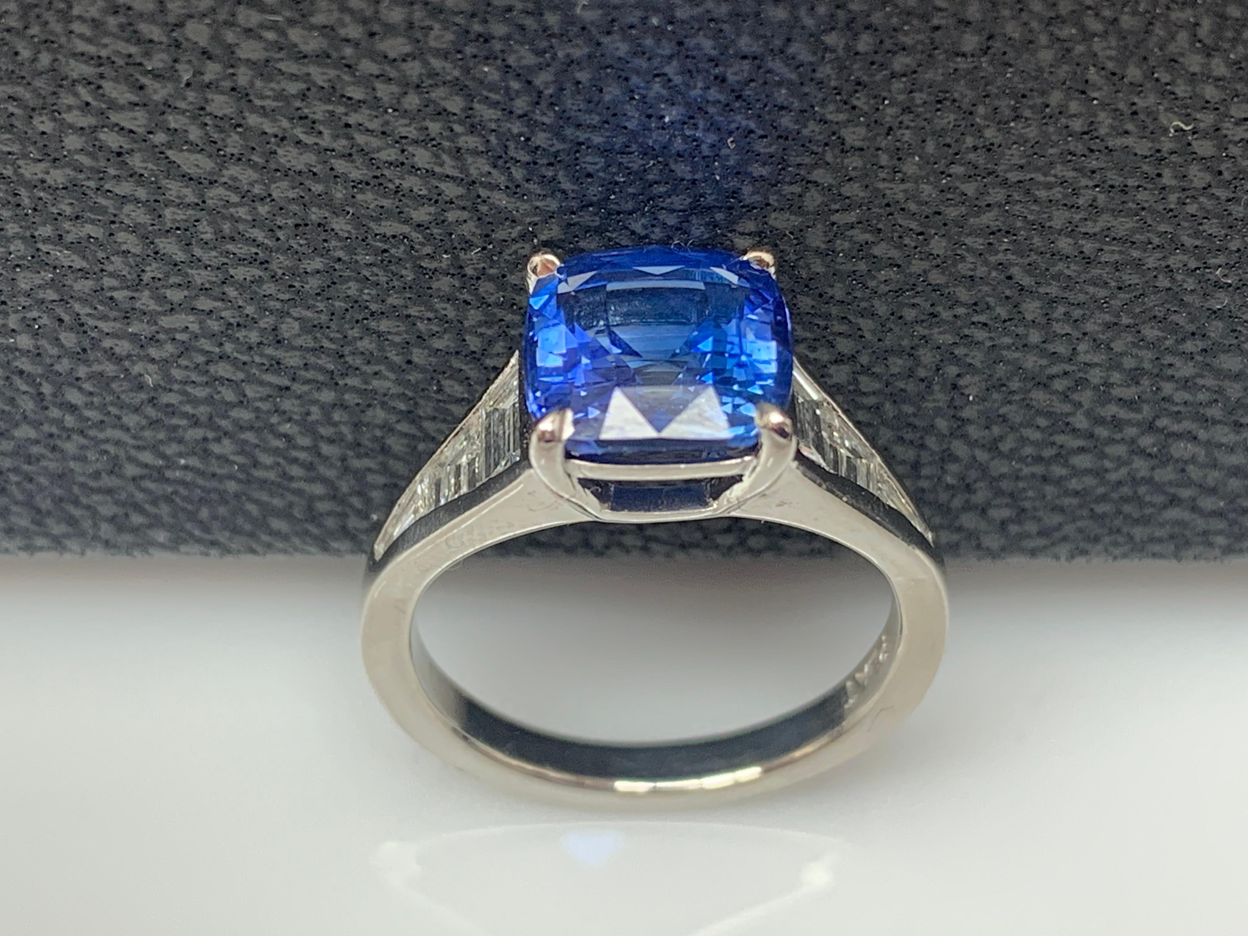 A stunning well-crafted engagement ring showcasing a 3.39-carat Cushion Cut Blue Sapphire. Flanking the center diamond are perfectly matched graduating step-cut diamonds, channel set in a polished platinum mounting. 6 Accent diamonds weigh 0.61