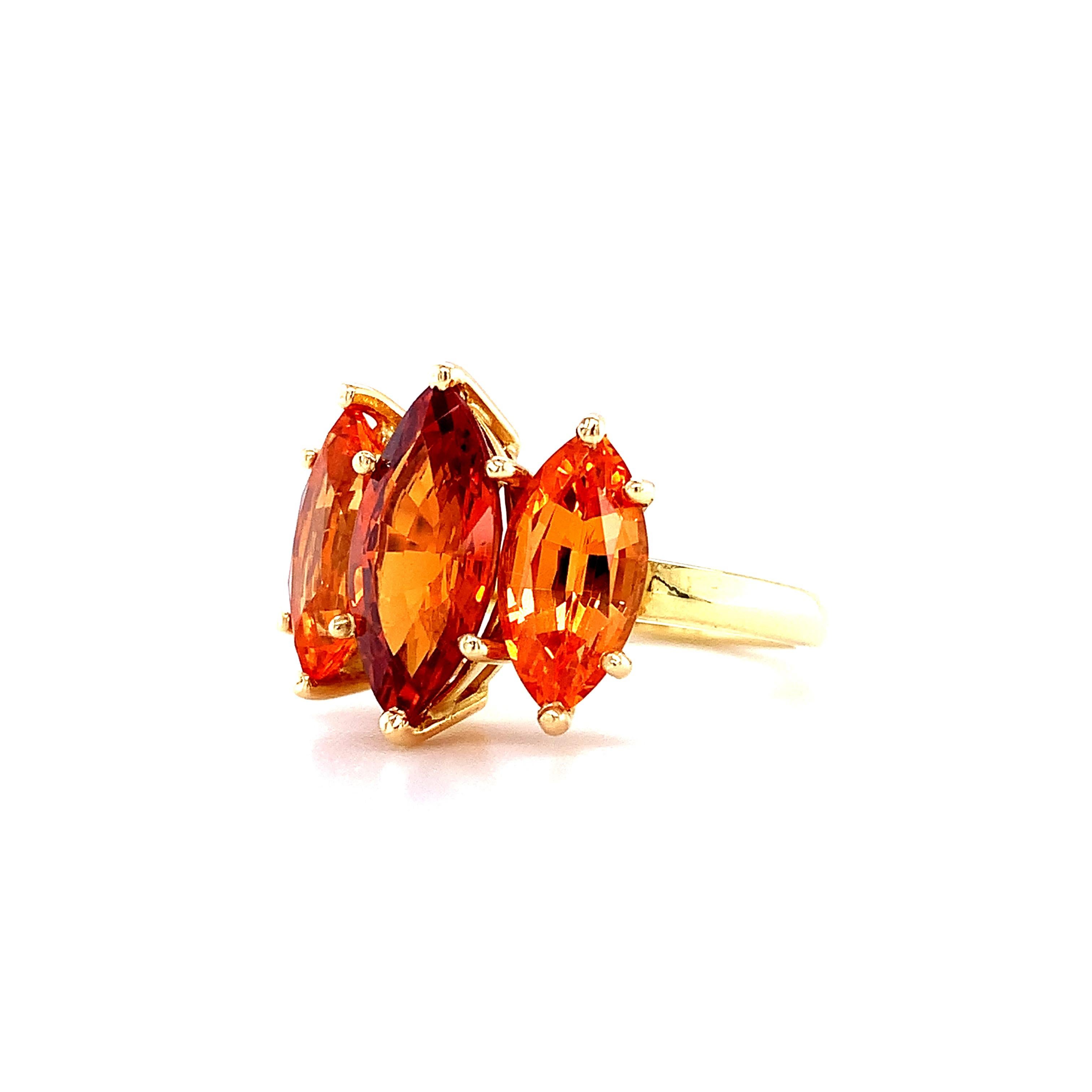 For the connoisseur of color! An unusual, richly colored hessonite garnet marquise is set with a pair of fine quality spessartite garnets in this not-so-classic, three-stone cocktail ring The 3.39 carat hessonite center stone has a strikingly