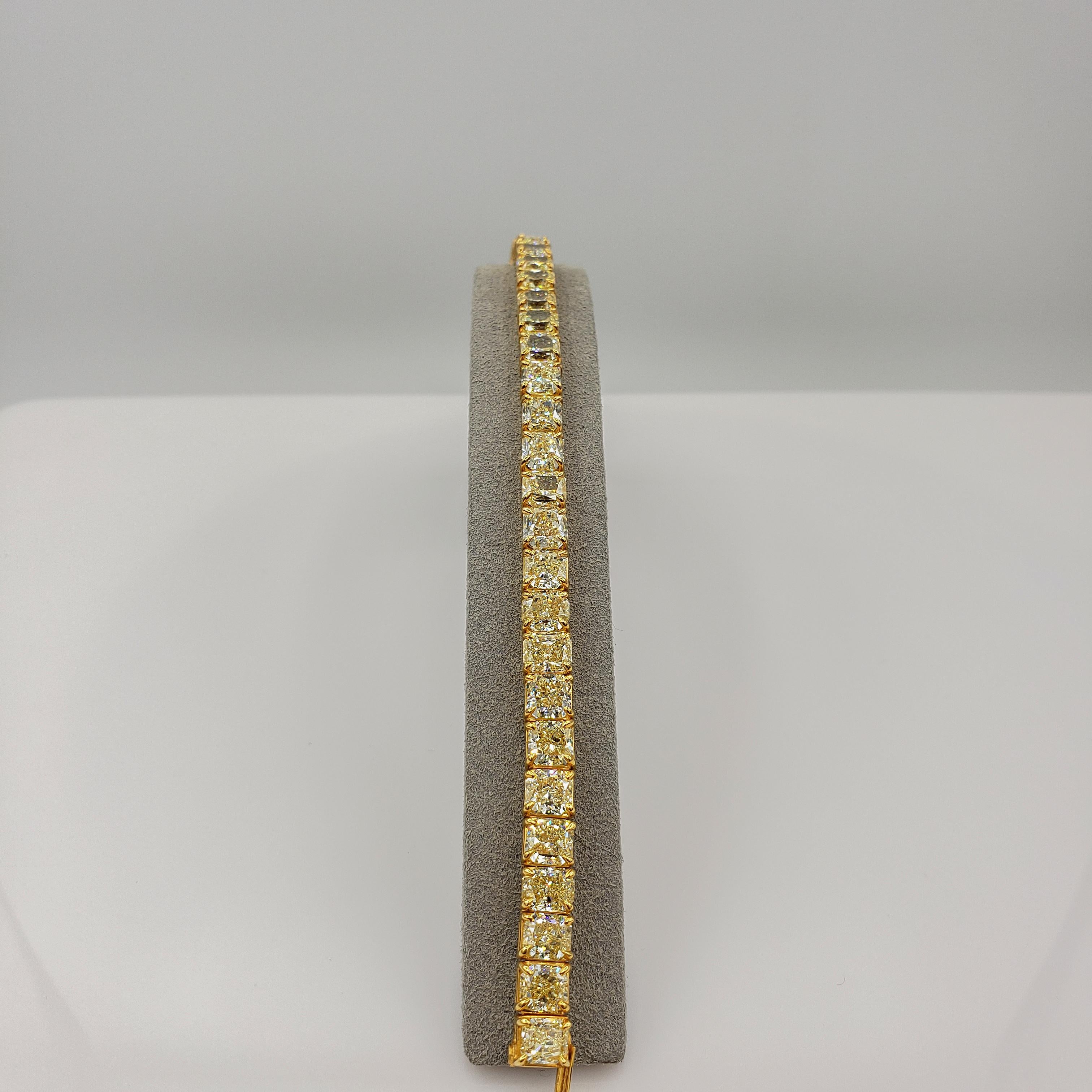 Well crafted and color rich tennis bracelet showcasing a row of 32 vibrant natural fancy yellow radiant cut diamonds weighing 33.97 carats total, set in a polished 18k yellow gold basket setting. 
