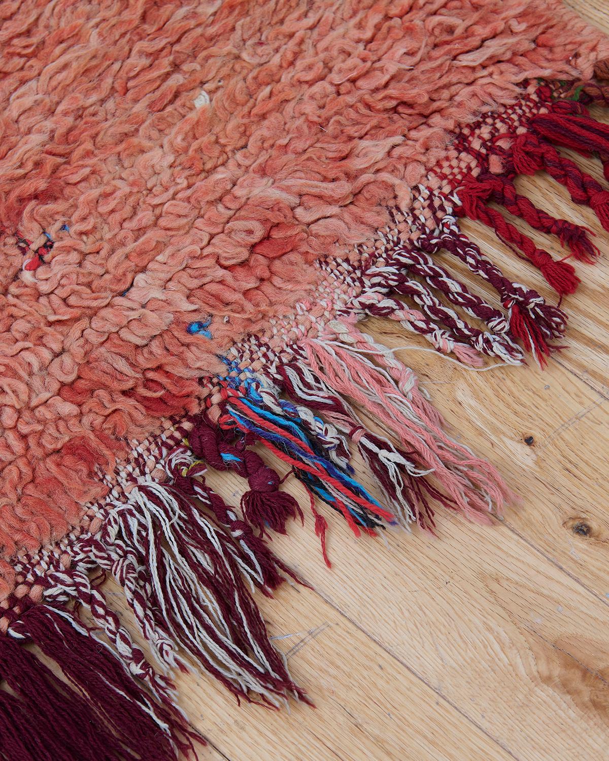 La alfombra Aster es una vibrante pieza marroquí vintage, expertamente tejida a mano por artesanos en Marruecos. Fabricada con lana de oveja 100% natural, esta preciosa alfombra presenta un tono rojo claro y multidimensional que aporta calidez y