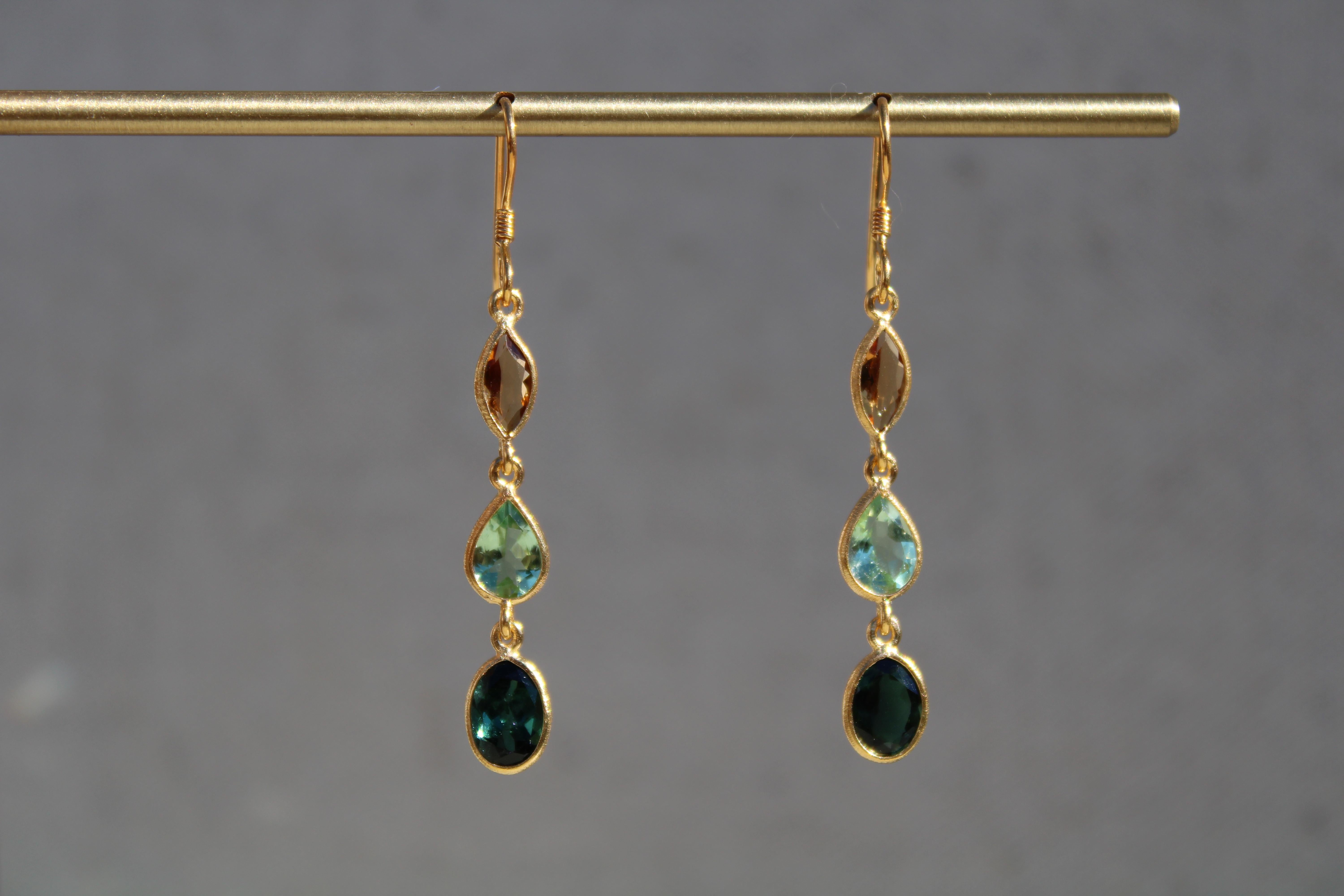 This pair of 3.4 ct three- stone dangle earrings are comprised of marquise honey Citrine, sage green Tourmaline pears, and hunter green Tourmaline oval cut stones. They are set in a 14K gold plated bezel minimal setting which allows for the stone to
