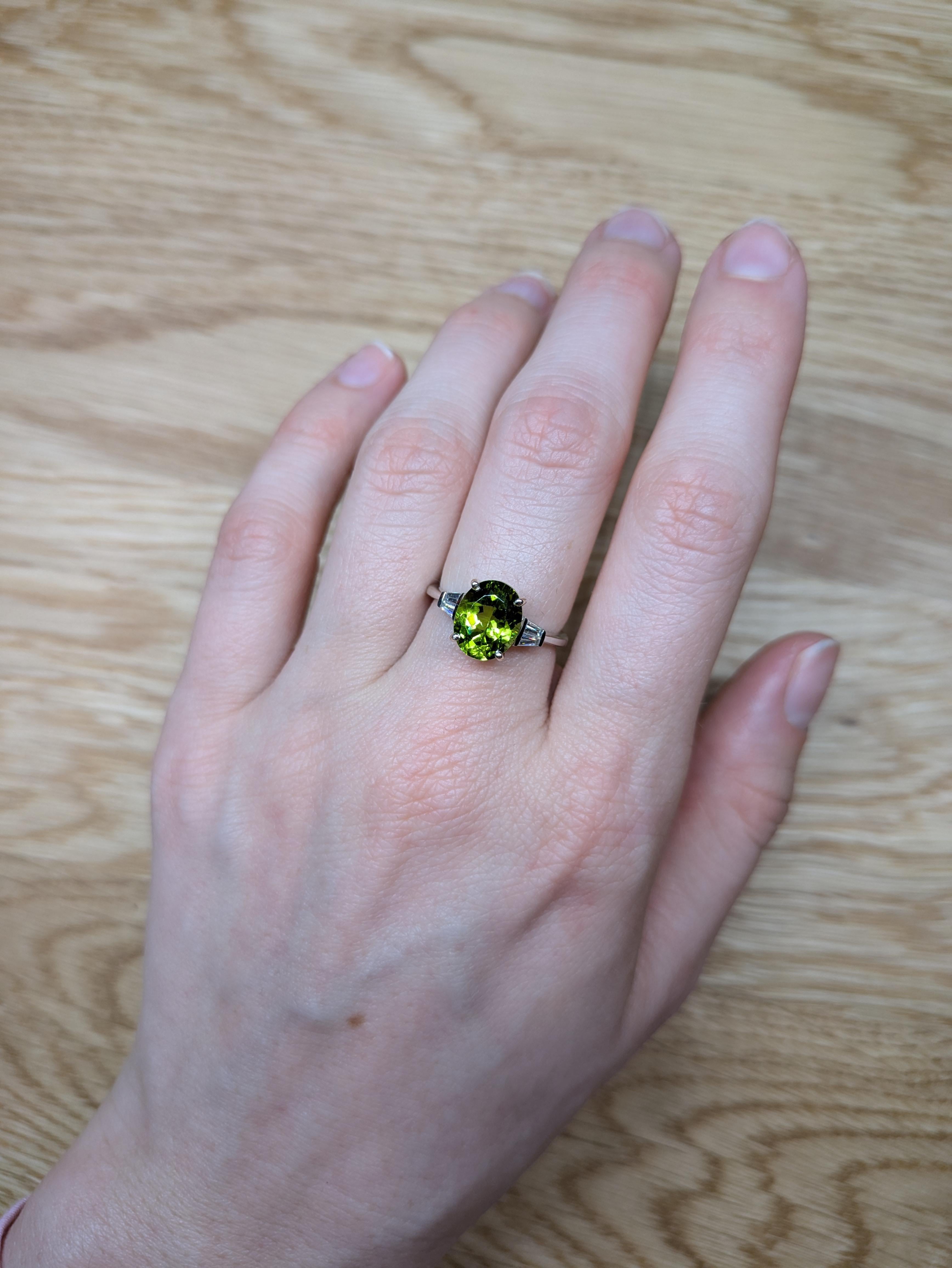 Un captivant péridot ovale de 3,39 carats est la vedette de cette élégante bague, encadrée par d'étincelants accents de diamants minés par la terre. Sertie en or massif 14 carats, cette pièce exquise est un hommage radieux à la pierre de naissance